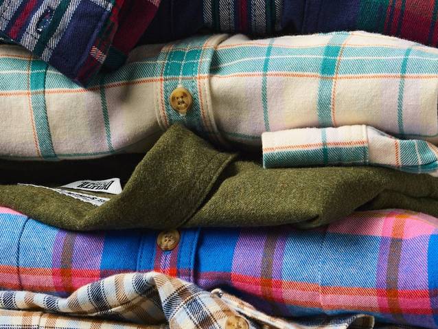 Women's flannels folded and stacked in a pile.