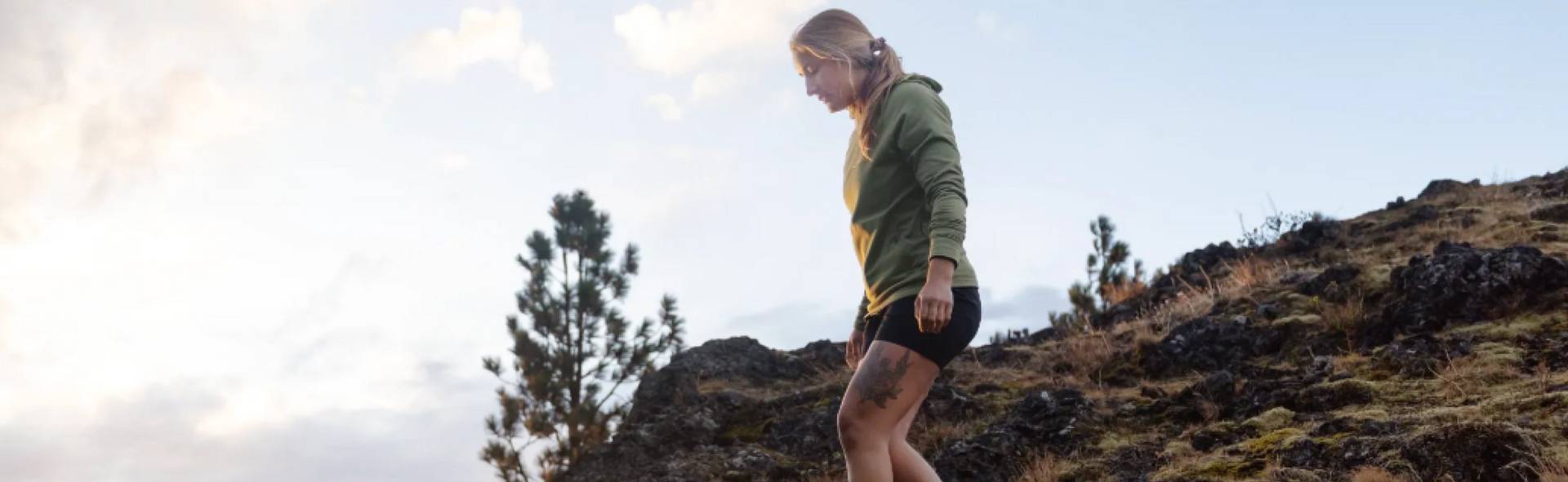 Woman wearing a green shirt and black shorts, hiking.