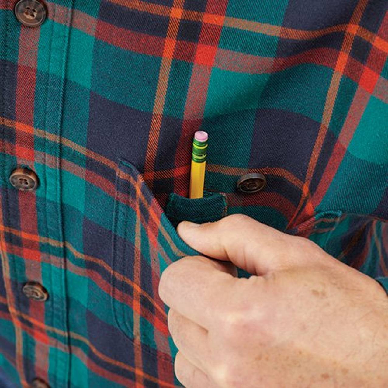 Close up of a hand holding open the breast pocket of a shirt to reveal a hidden pocket for a pen or pencil