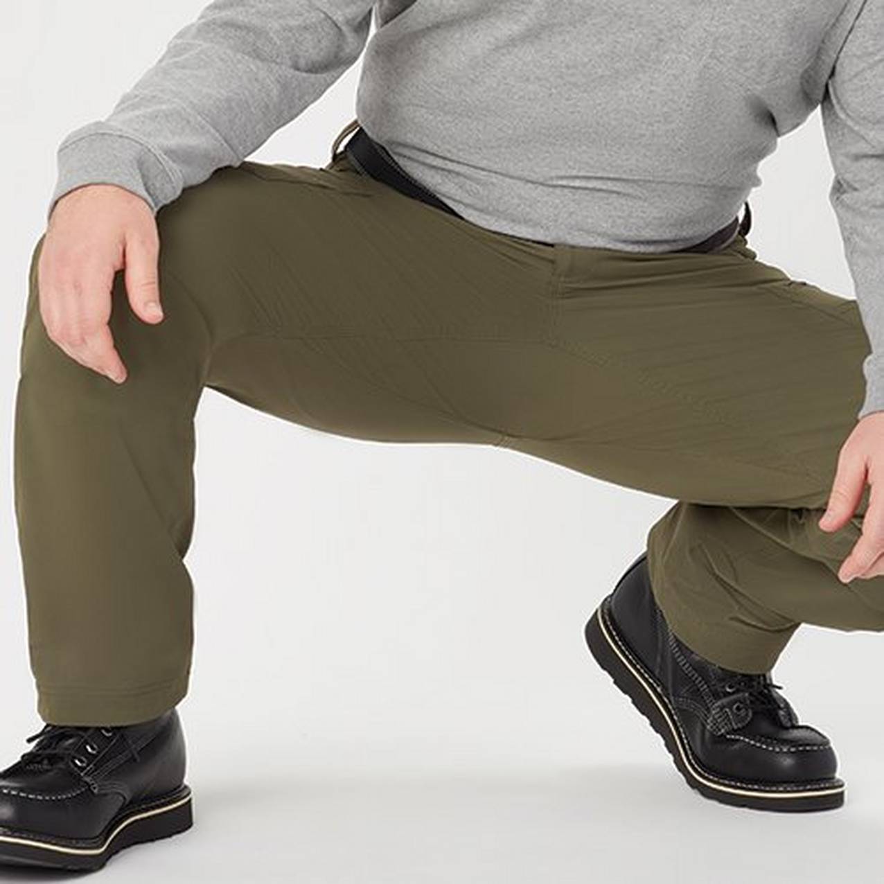 Close up of a man crouching down to show the free range of motion in the pants worn