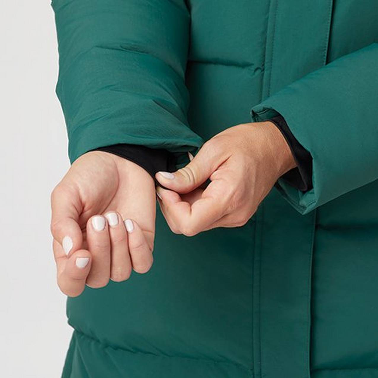 Close up of hands pulling the interior storm cuff down from inside the cuff of the jacket sleeve