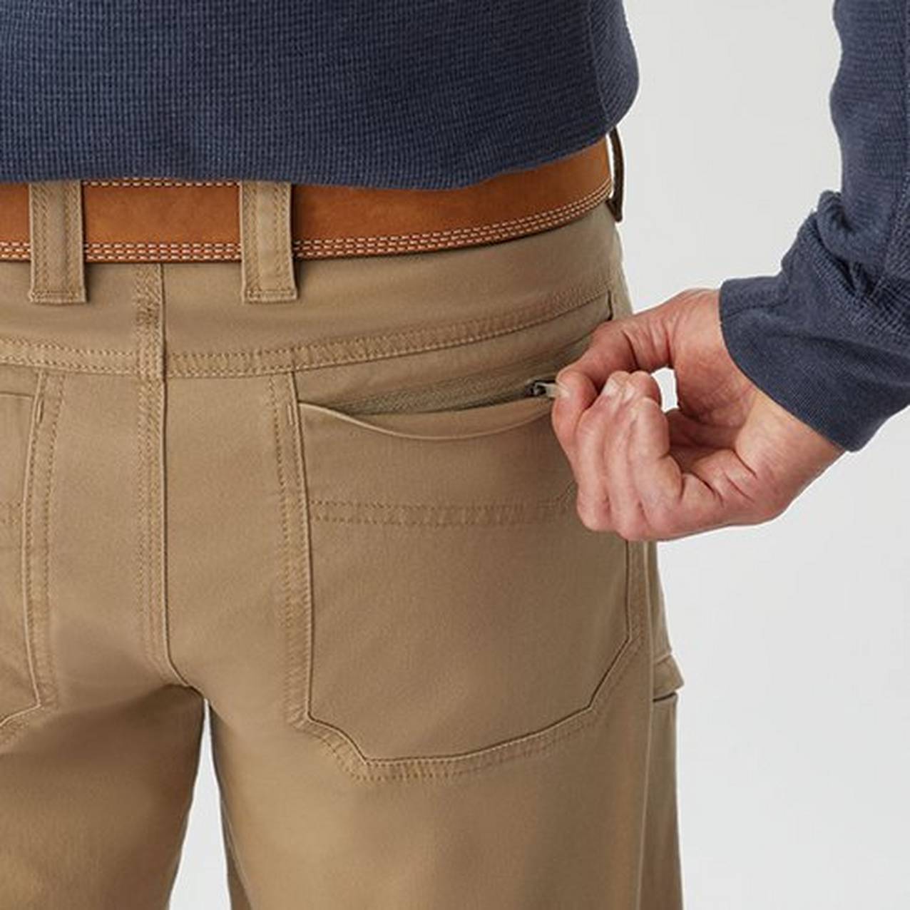 Close up of a hand zipping a rear pants pocket closed