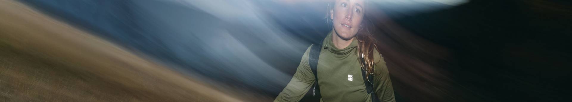 Woman wearing a green shirt and black shorts, hiking.