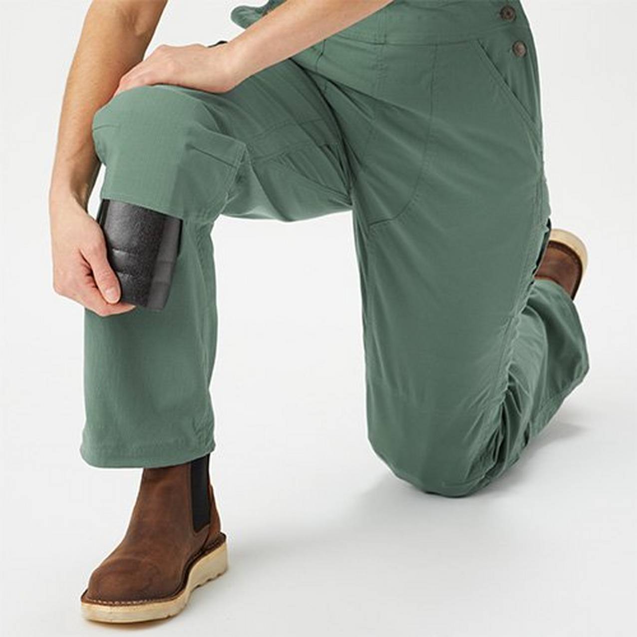 Image of person crouching adding knee pads to overalls