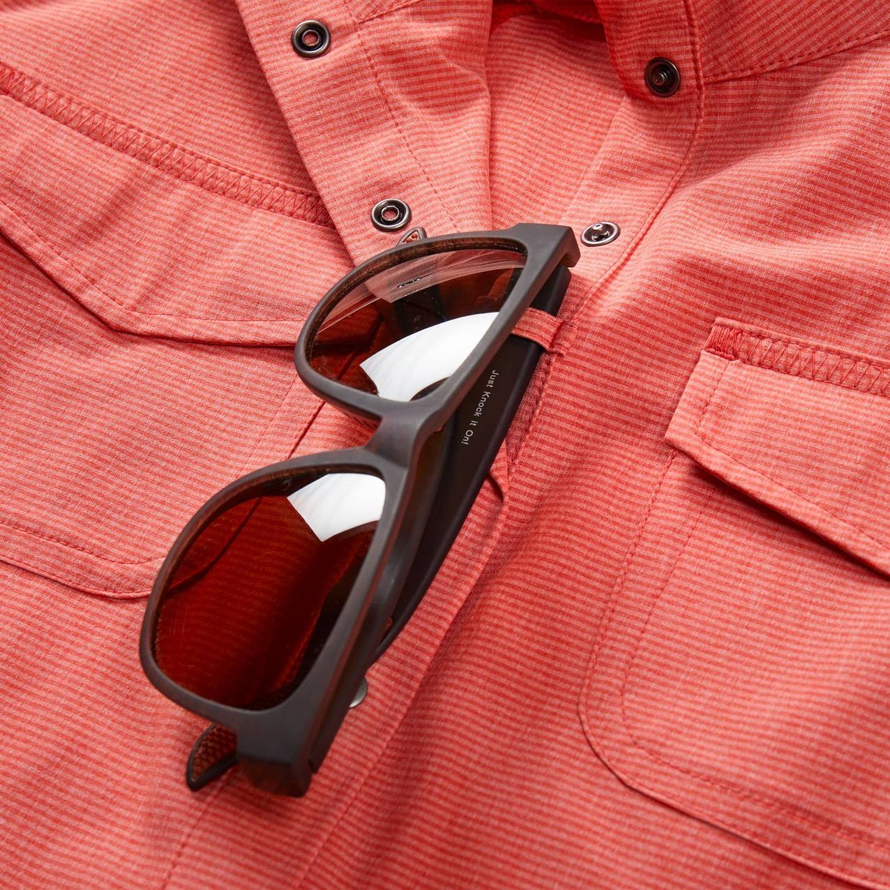 Sunglasses looped through fabric loop on shirt