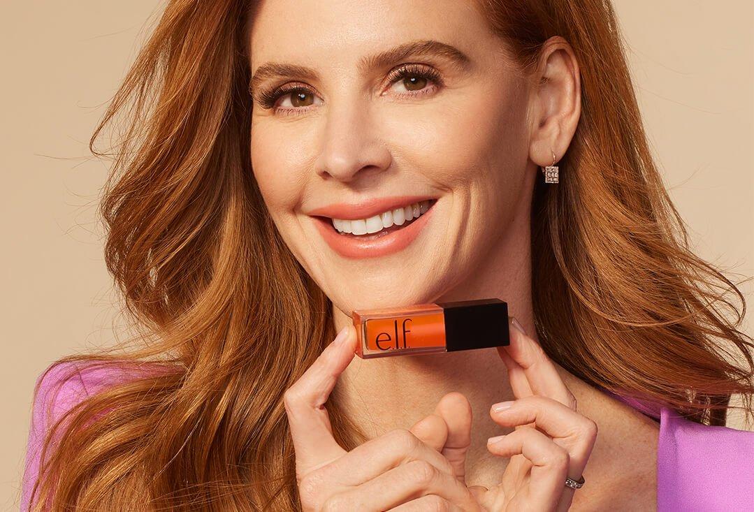 Sarah Rafferty, lady in pink and stenographer, is holding an             e.l.fs. Cosmetics lip oil