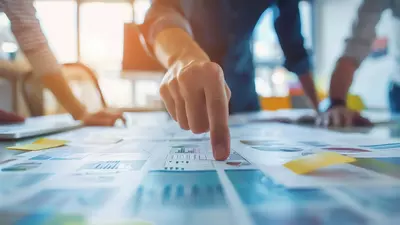 closeup hand pointing business documents table team meeting modern office setting highlighting teamwork planning