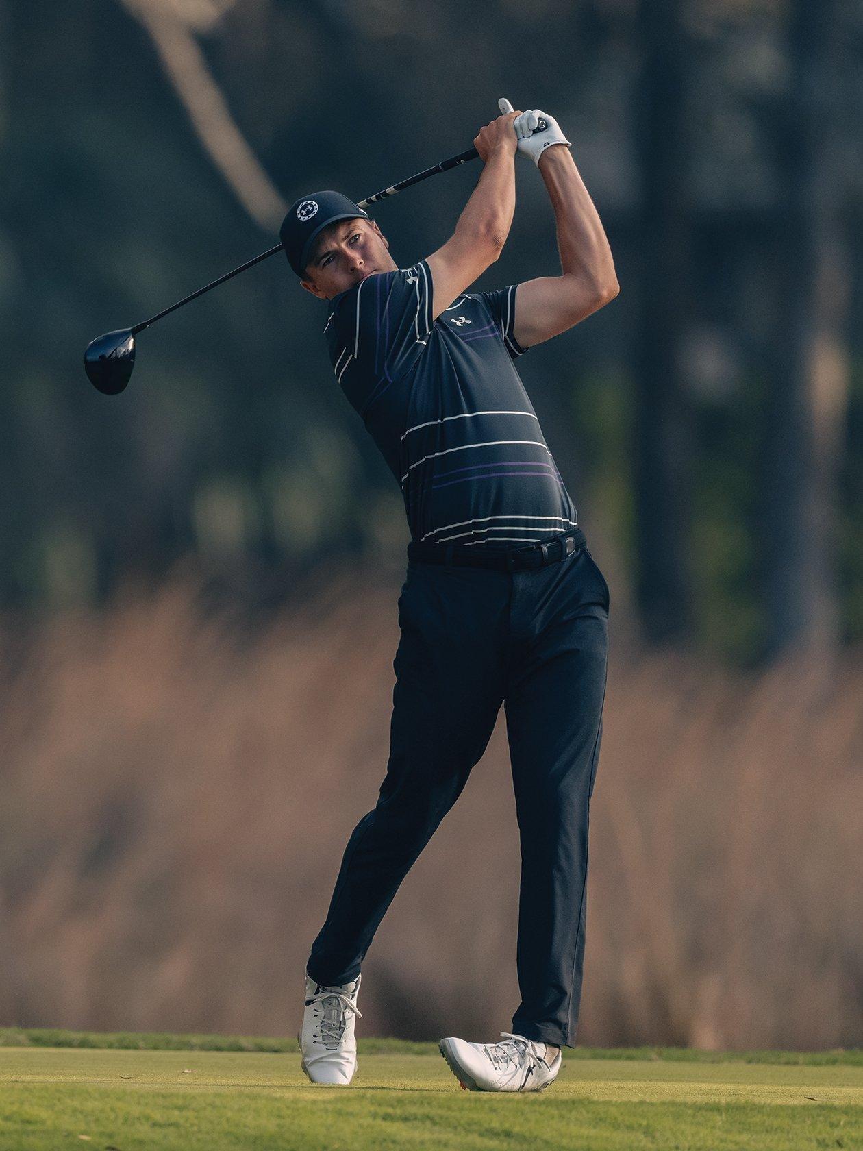 a man in black shirt and black pants swinging a golf club