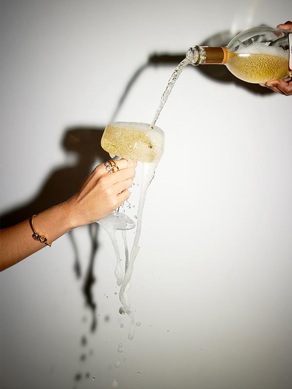 A bottle of sparkling wine being poured into an overflowing glass