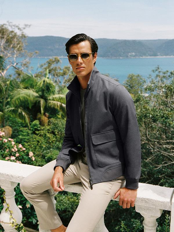 Man in a grey jacket with a scenic view behind him