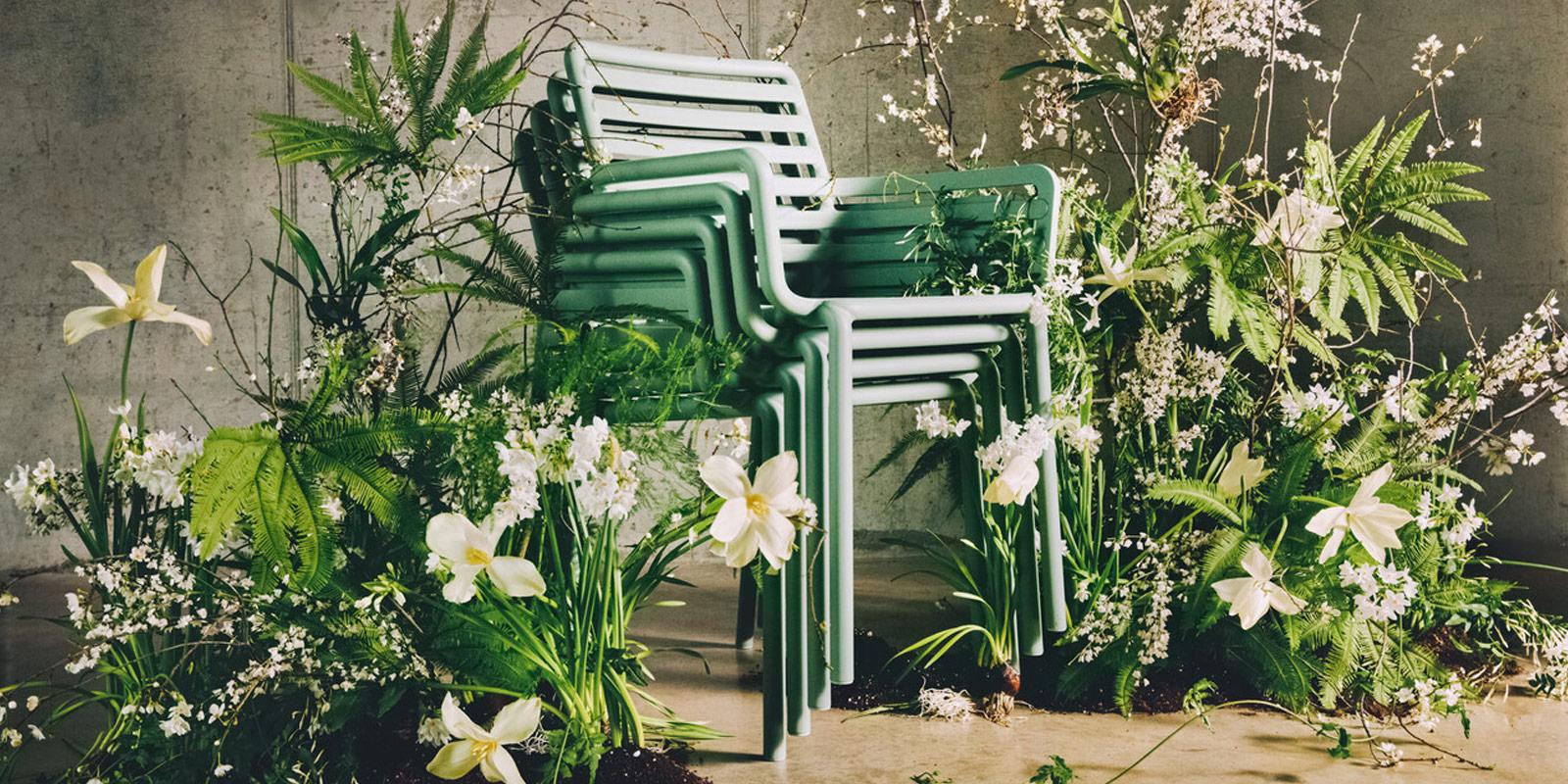 Garden chairs stacked up with flowers around them