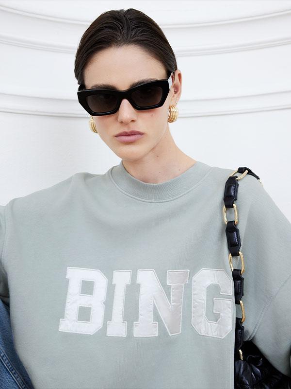 An Anine Bing logo sweatshirt on a dark-haired woman.