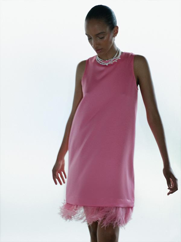 woman wearing a pink dress with a feathered hem
