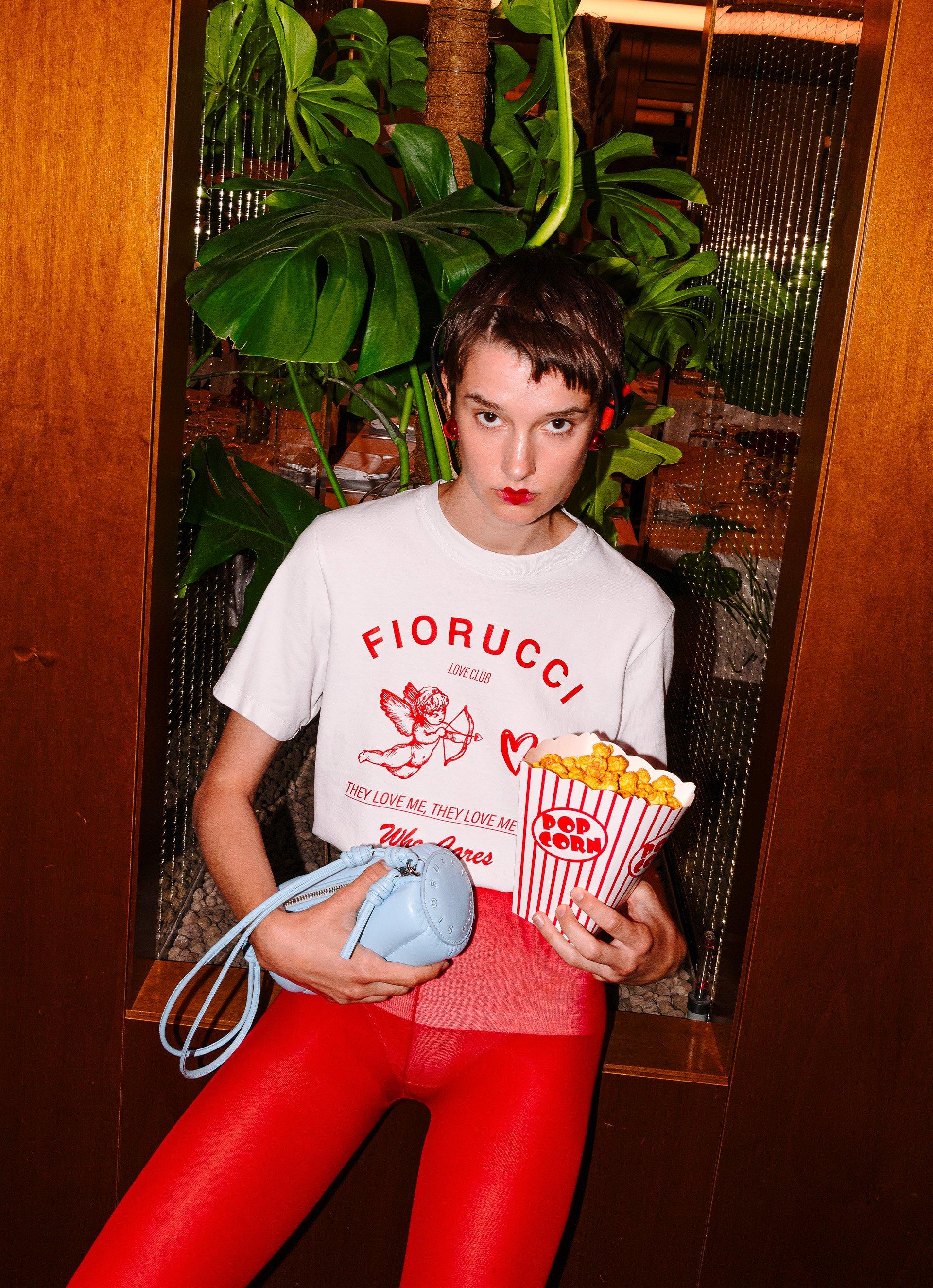 Model is wearing the Cupid Love Club T-Shirt in White and the Mella Leather Mini Bag Blue.