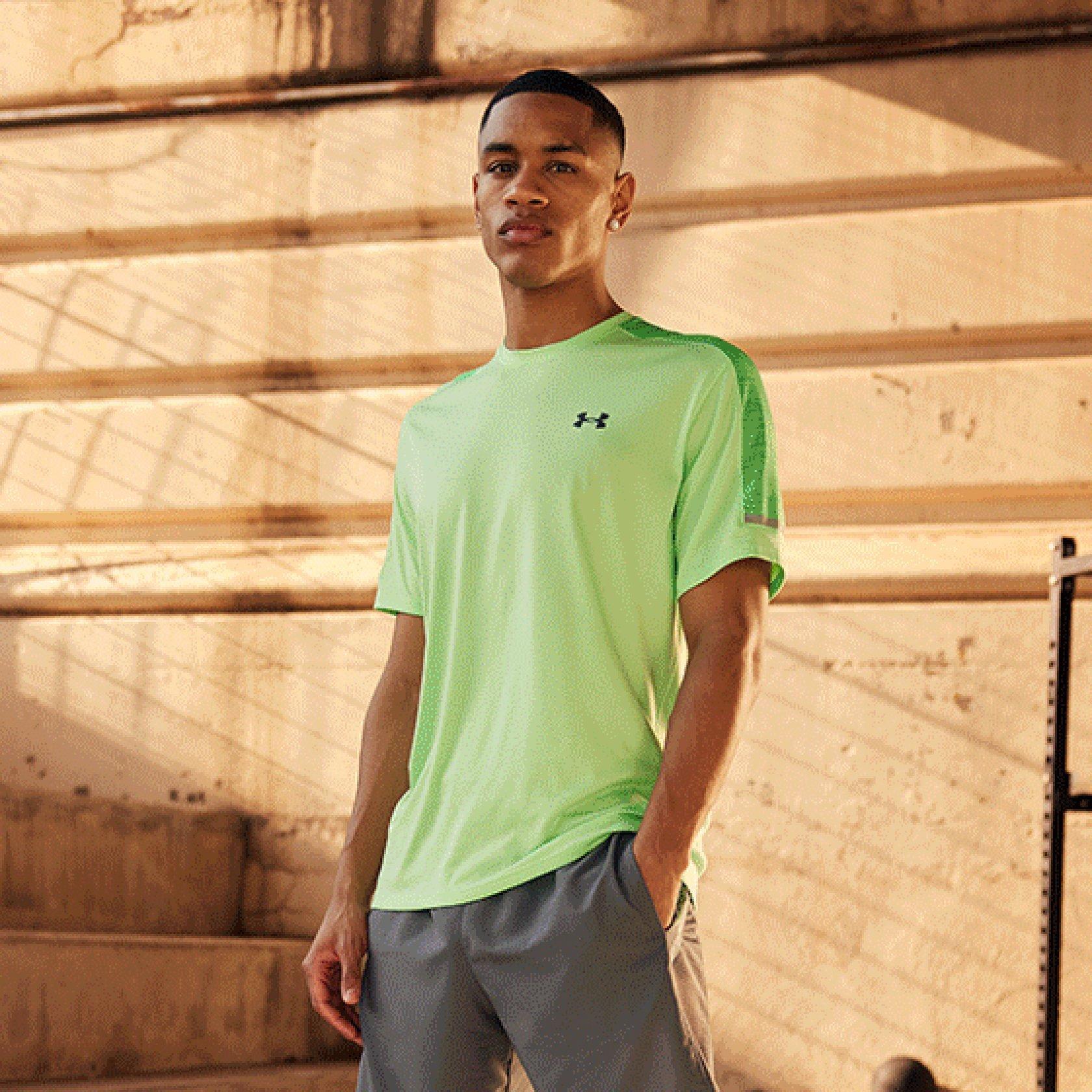 Hombre sentado en unas escaleras de hormigón con el conjunto completo de Under Armour