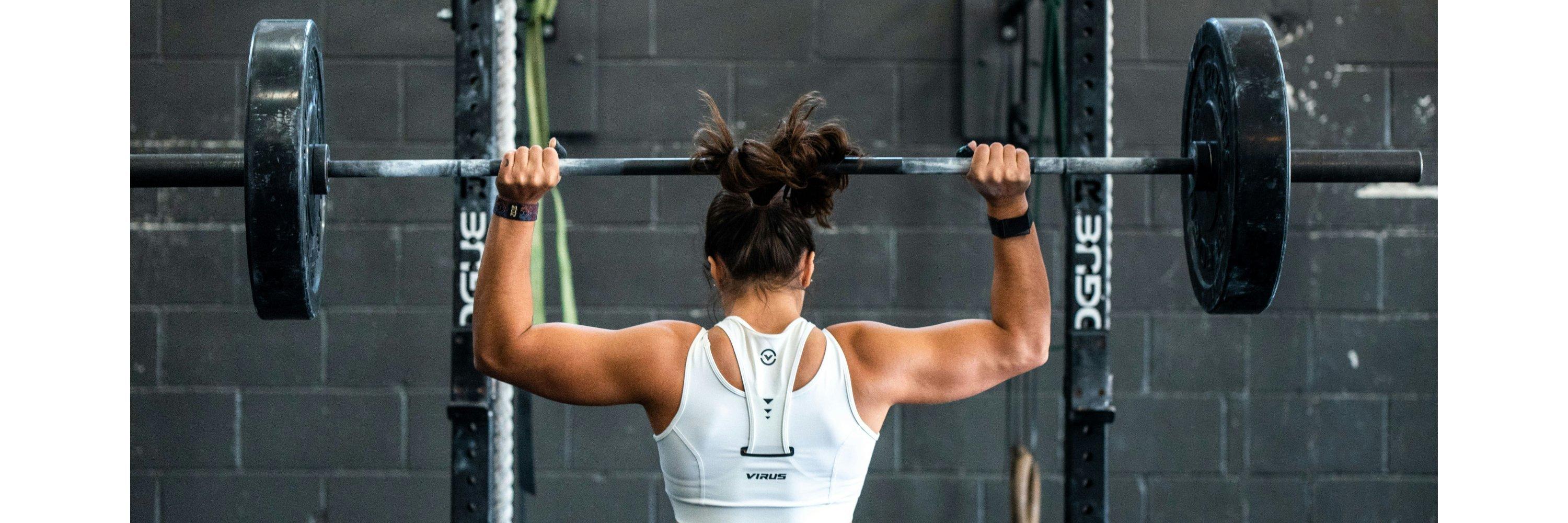 Woman lifting barbell weight from a squat rack in a gym