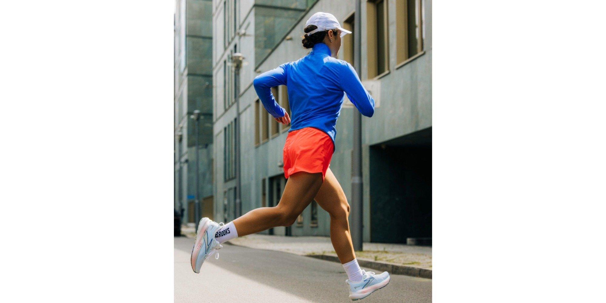 Woman wearing running gear running in a city setting, facing away from the camera
