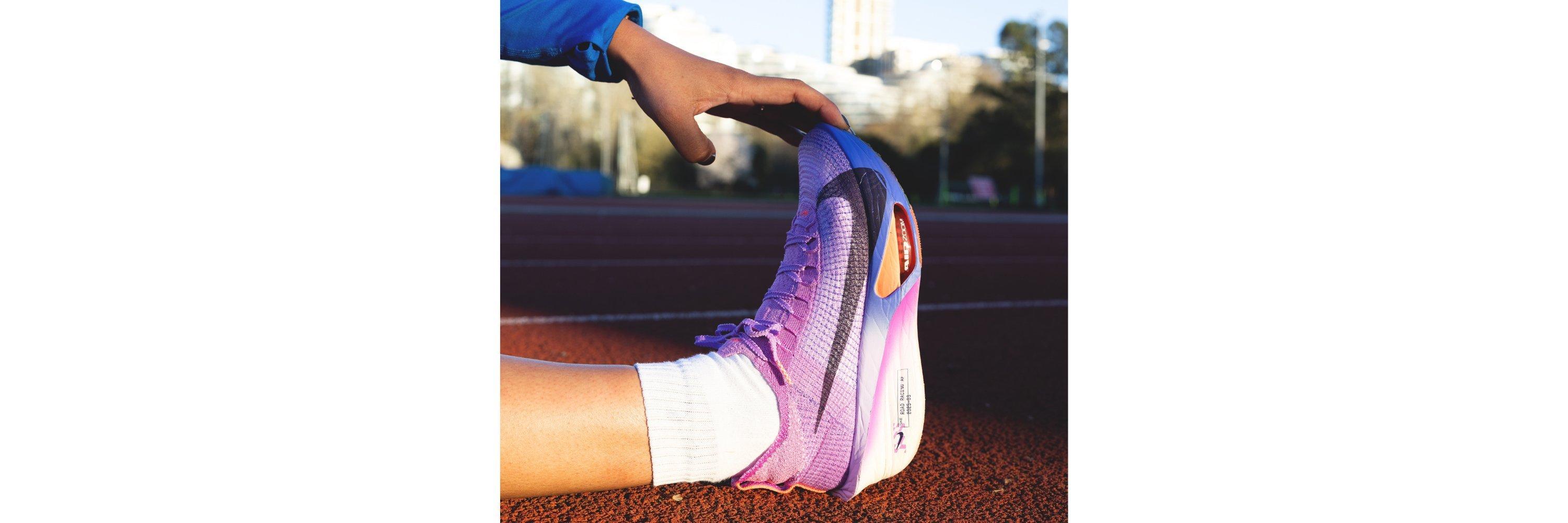 A picture of someone stretching pink Nike running shoes whilst on a runners foot at a sideways angle