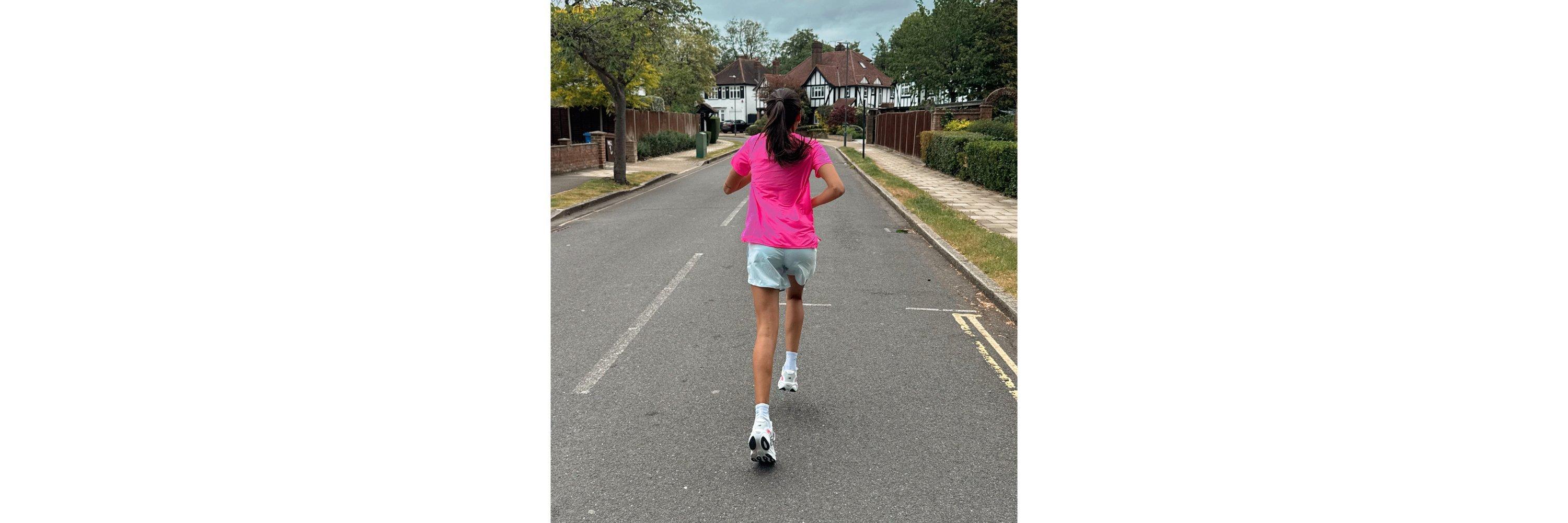 A women wearing pink running clothes running on a road
