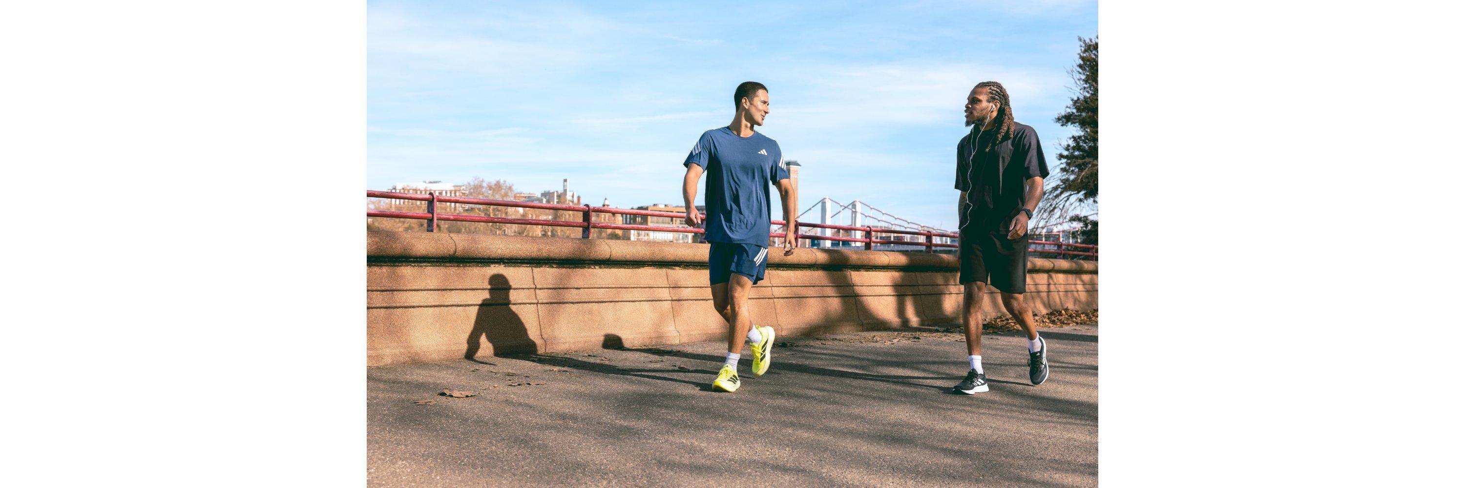 Two people wearing running clothing walking alongside a scenic background