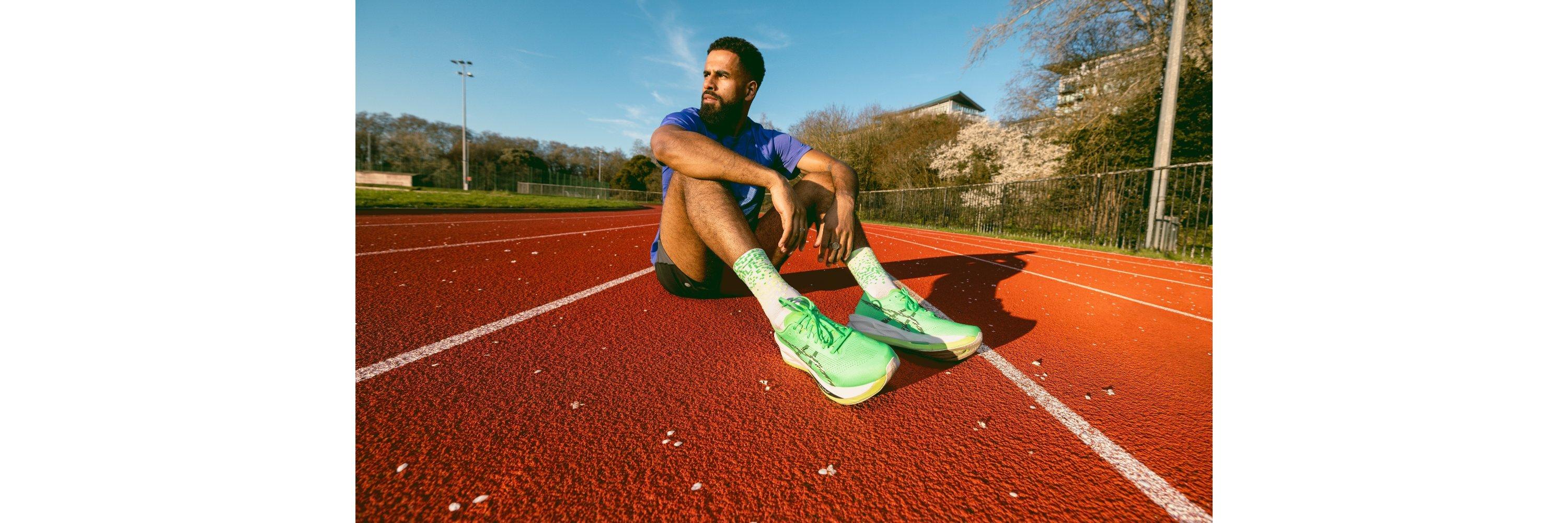 Man wearing running shoes sitting on a running track