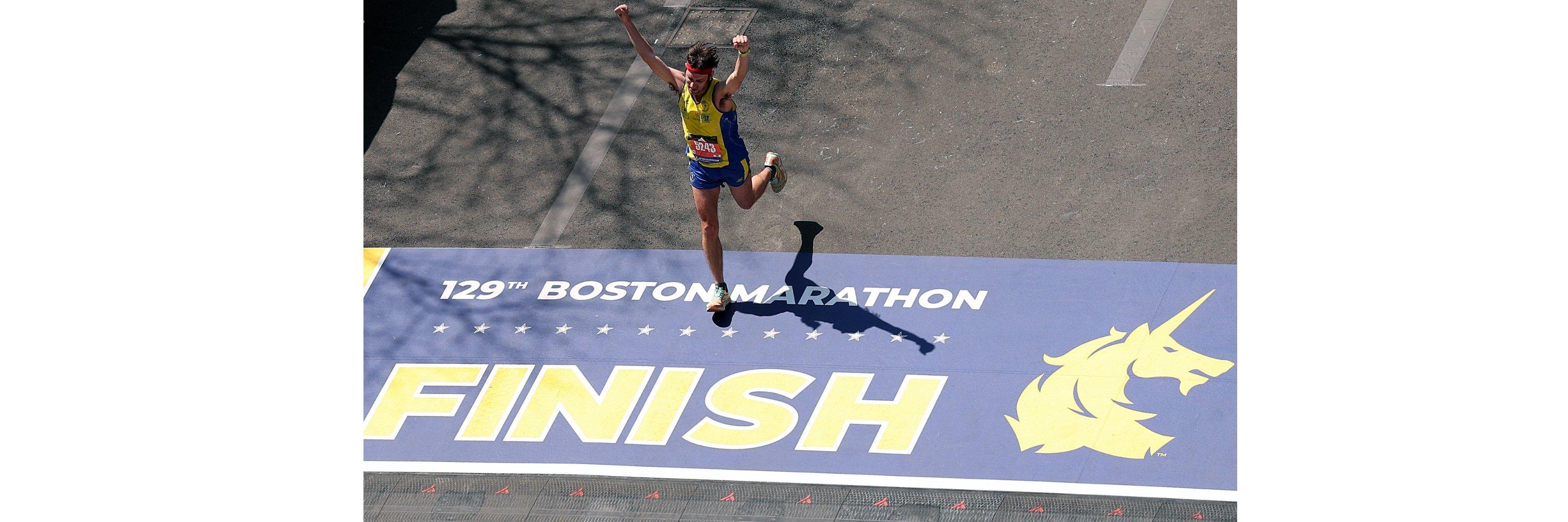 A man wearing running gear crossing the finishing line of the Boston marathon