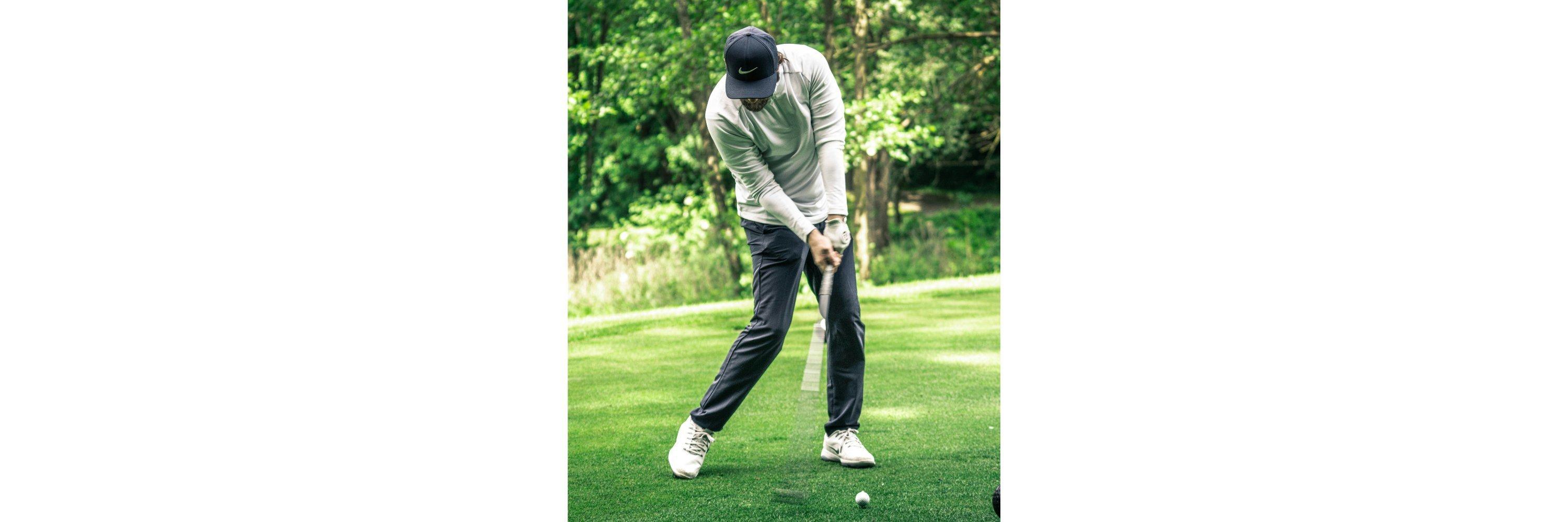 A man wearing golf clothes putting a golf ball