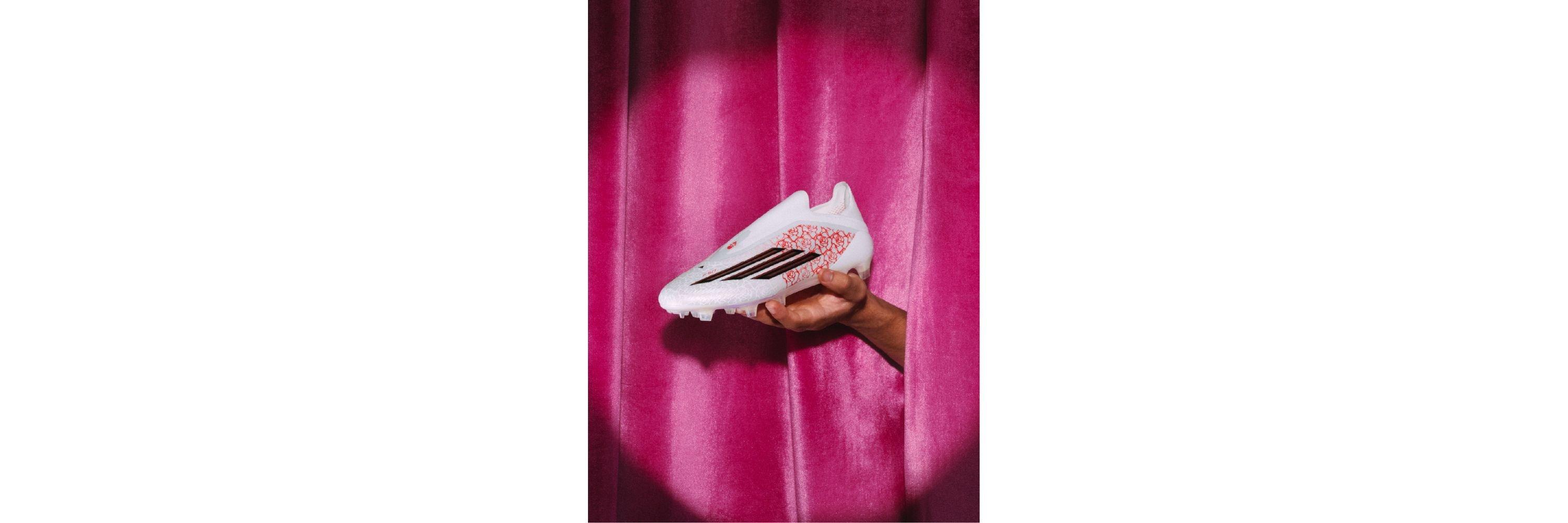 An image of the adidas F50 Lamine Yamal Edition football boots behind held against a stage curtain
