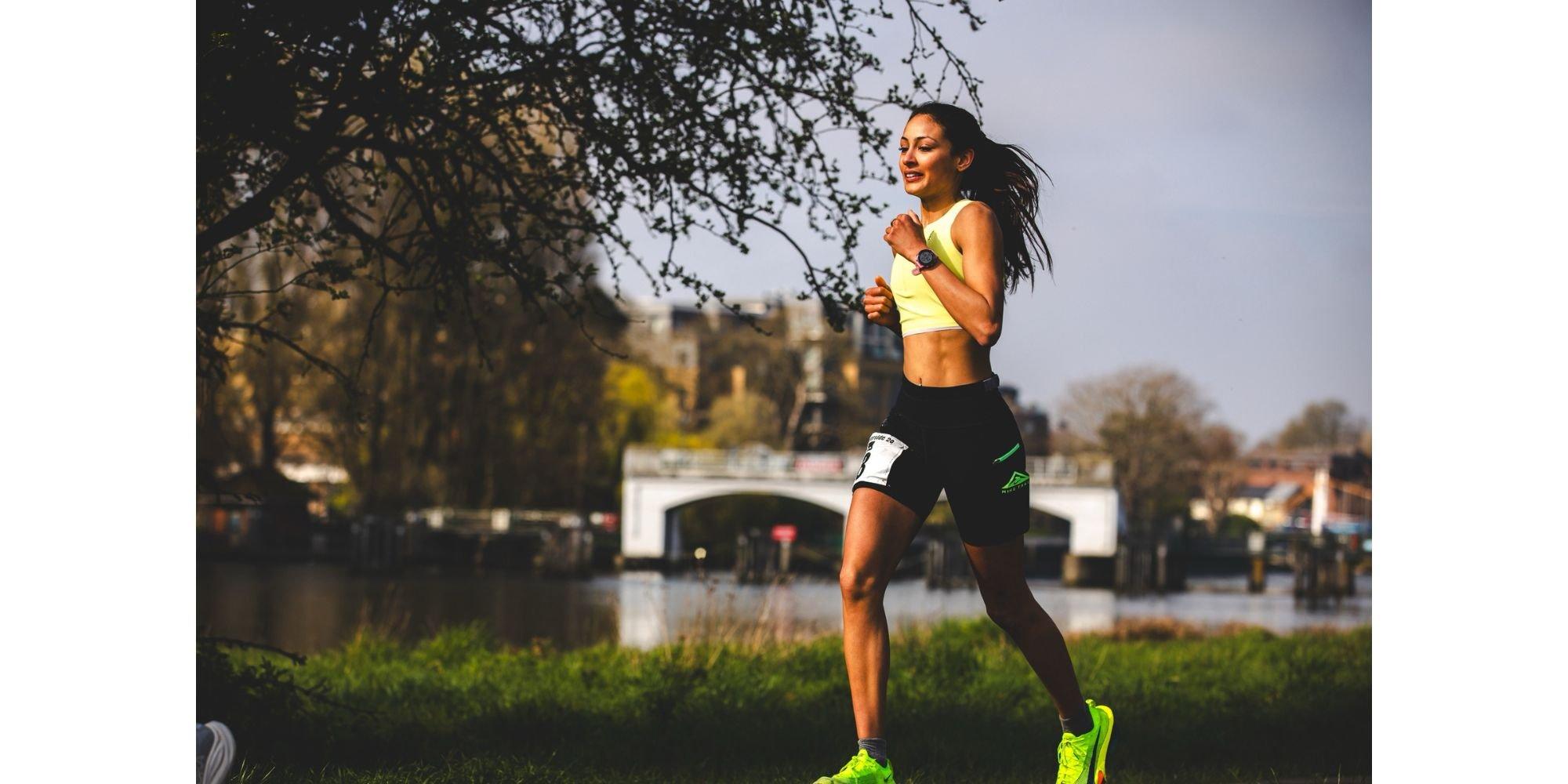 Priya running alongside a river wearing running clothes and trainers