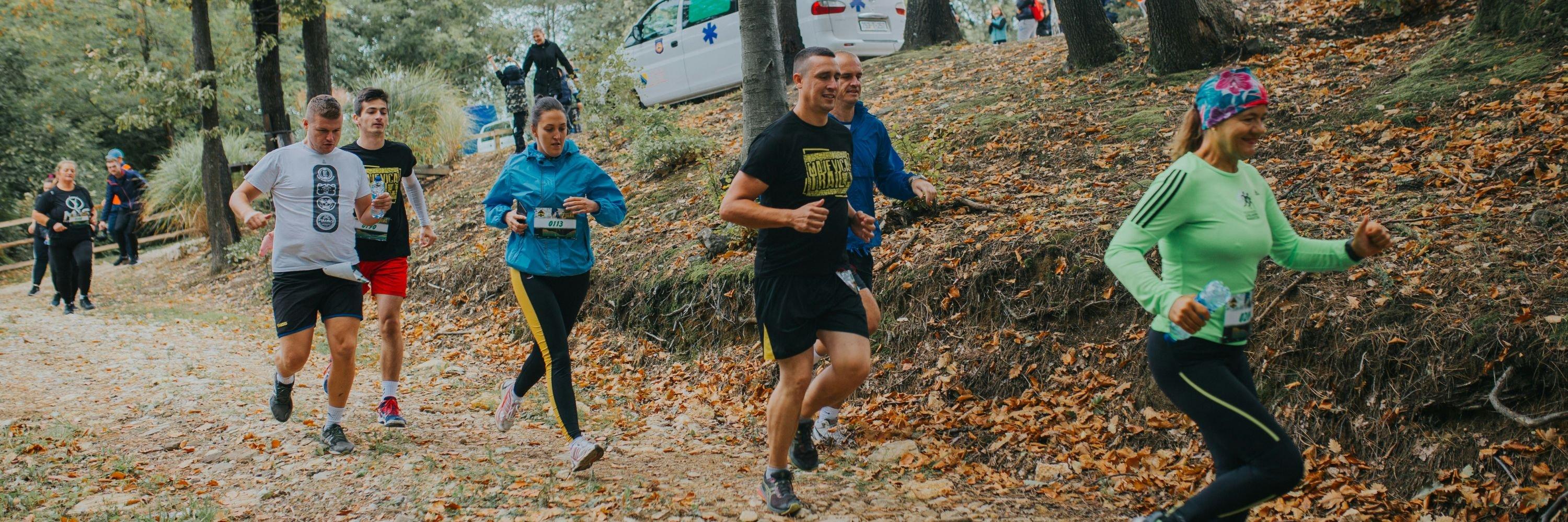 People running along a path covered in leaves, wearing running gear