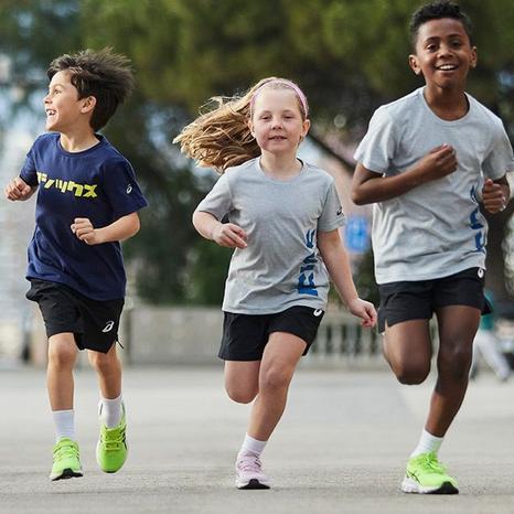 Bambini che corrono insieme all'aria aperta in abbigliamento e calzature Asics.