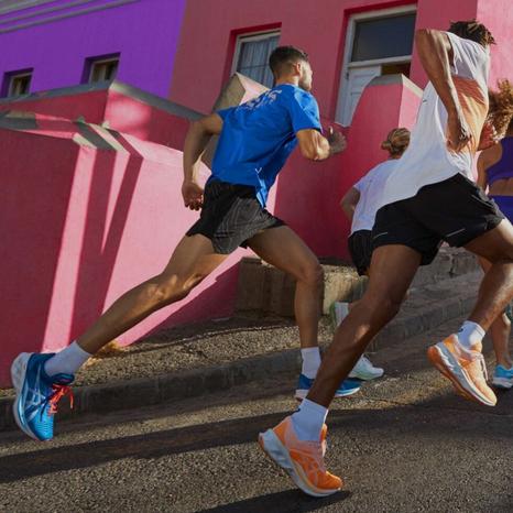 Ragazzi che corrono mentre indossano magliette a mezze maniche colorate di Asics.