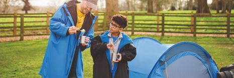 People eating outside of a tent while camping