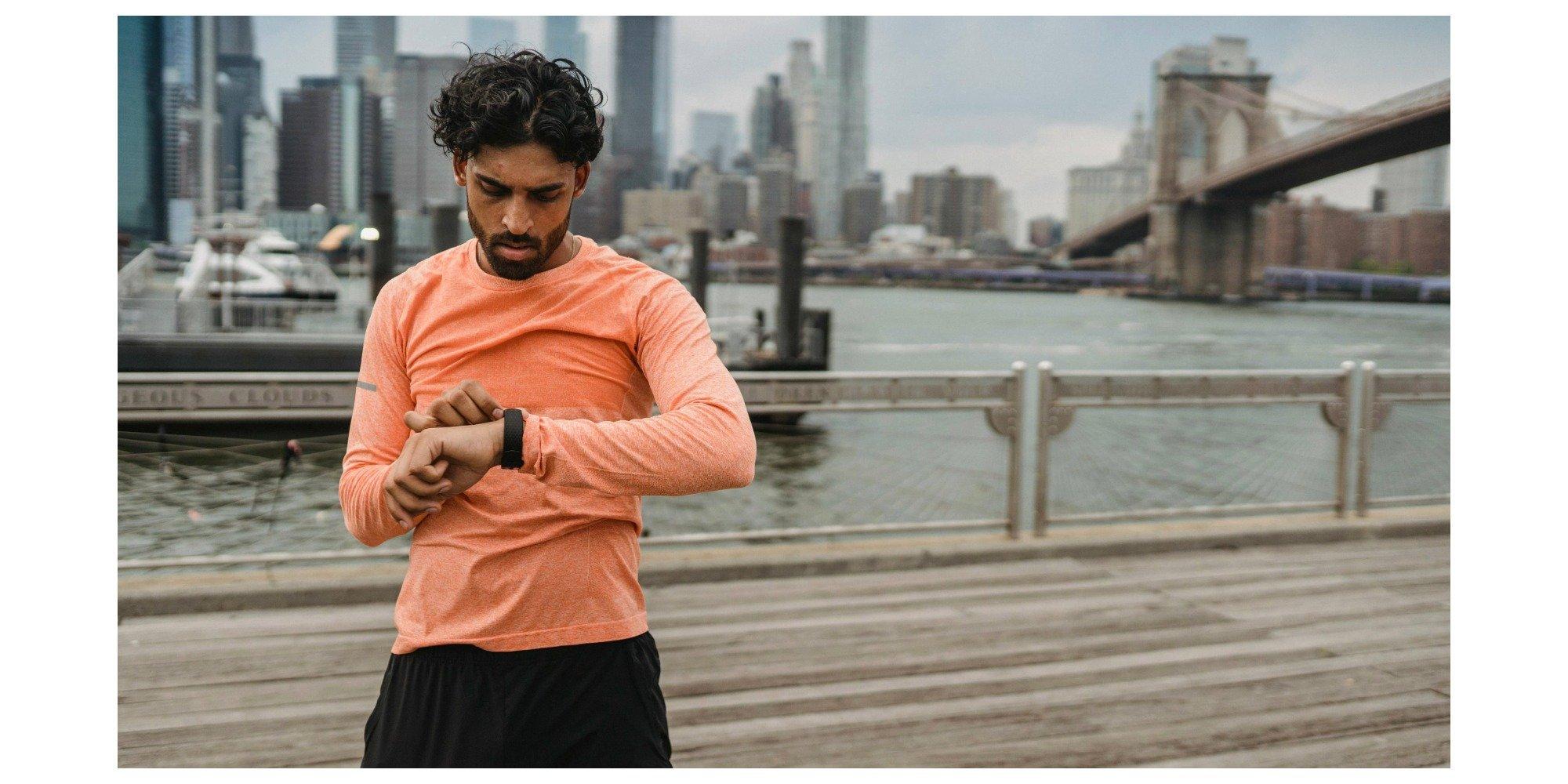 Man wearing running gear, looking at his running watch on his wrist