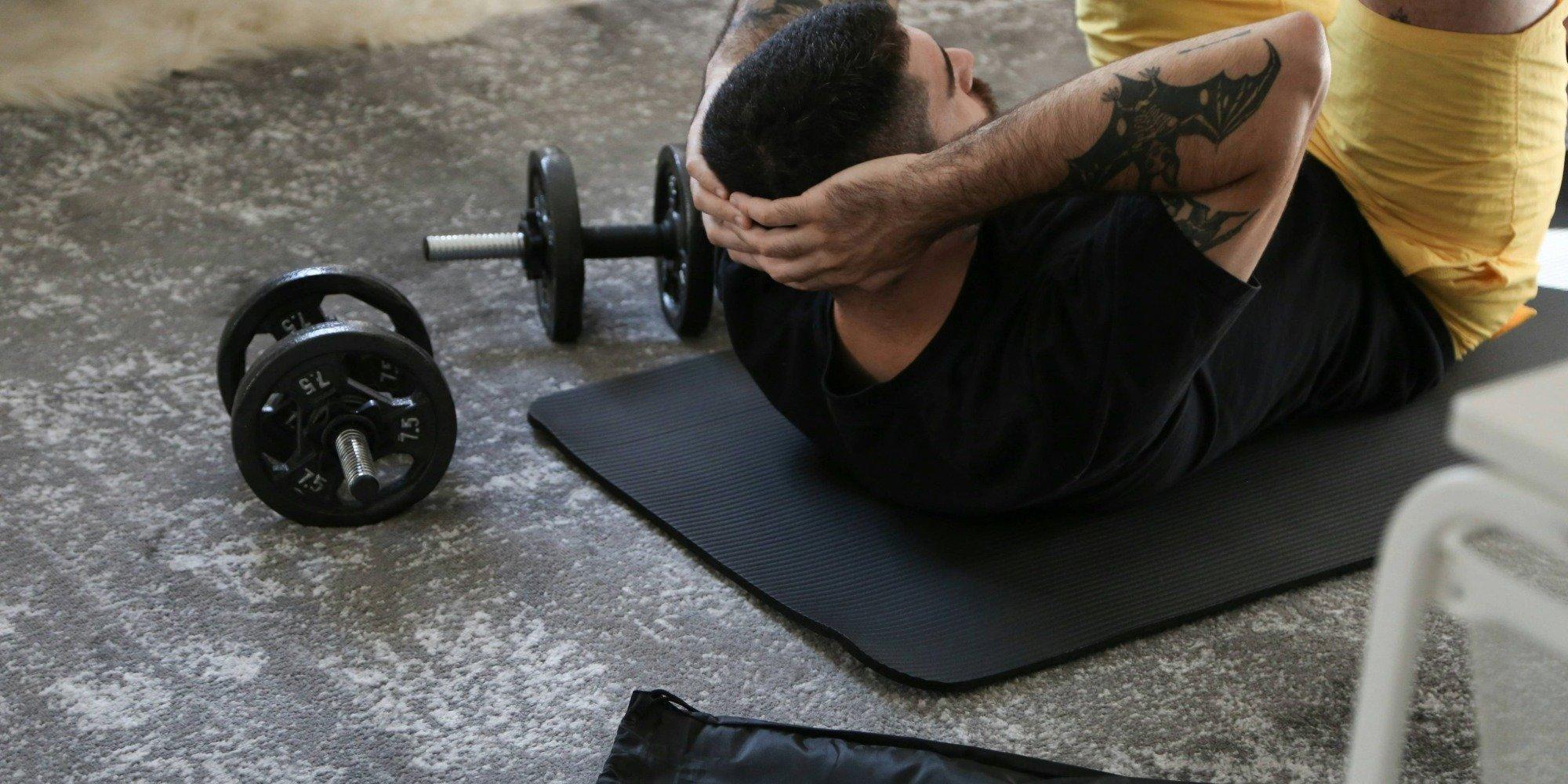 Man doing a sit-up with gym weights lying nearby