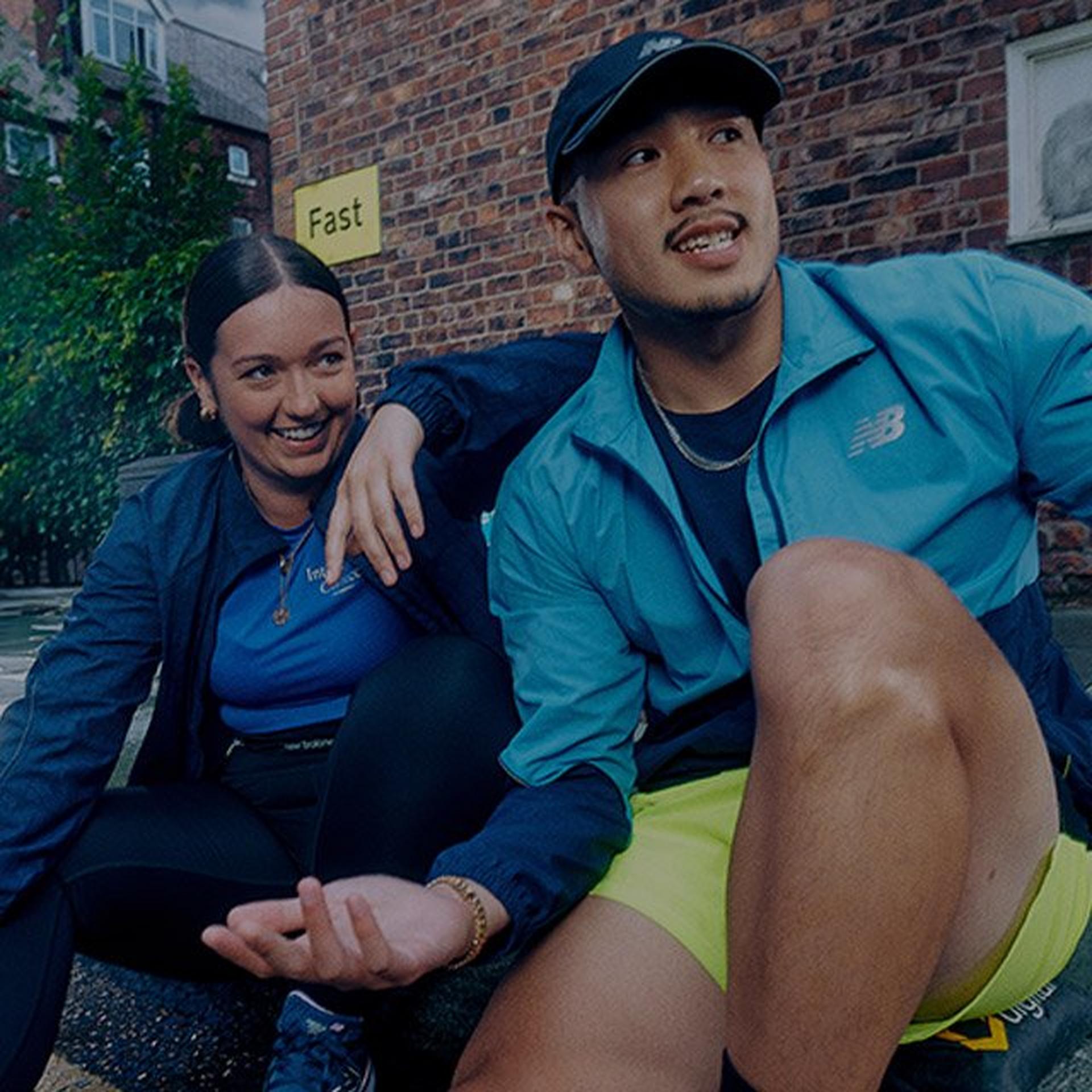 Couple sitting on the side of the road in New Balance running gear