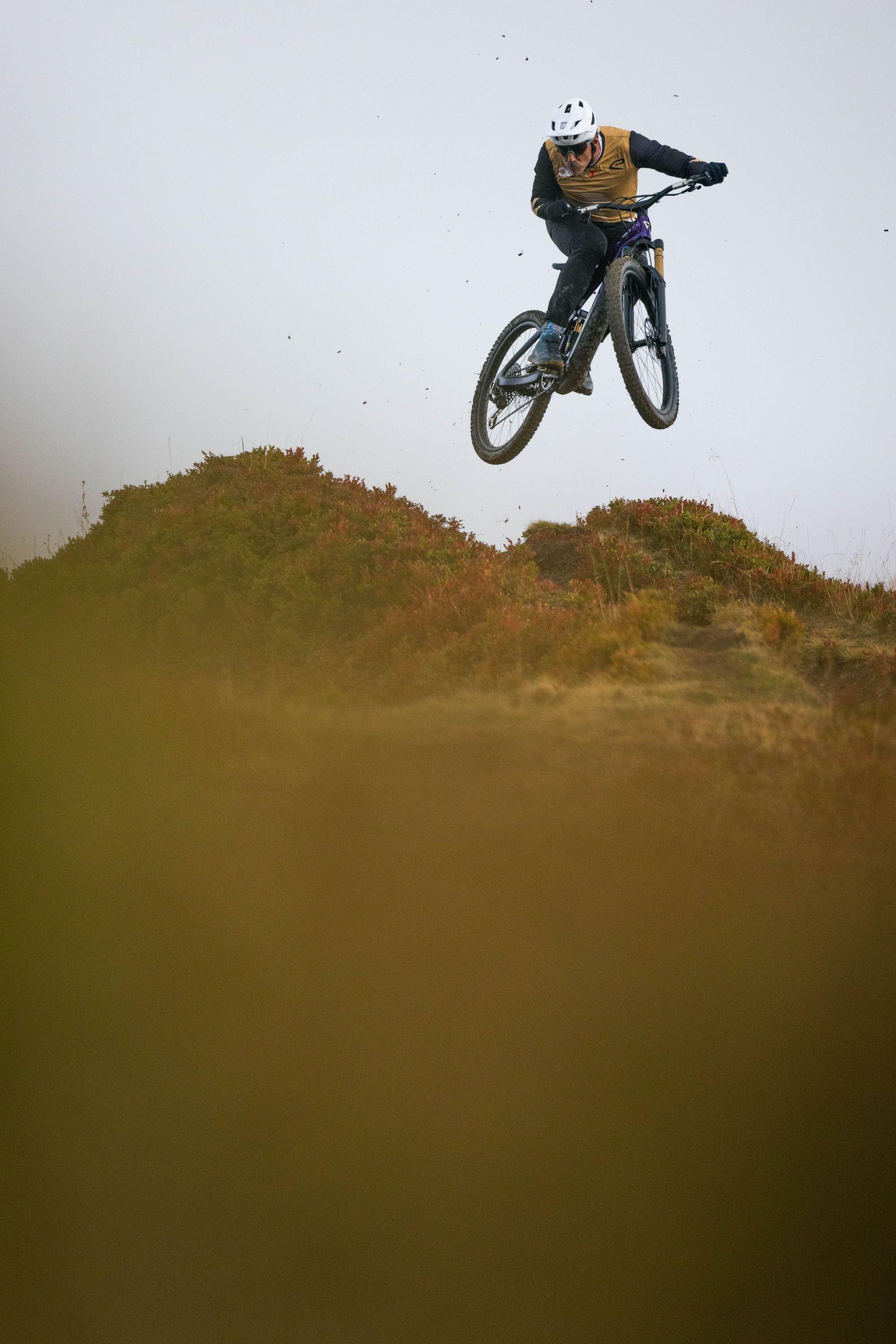 a man on a mountain bike jumping a hill on a sunny day