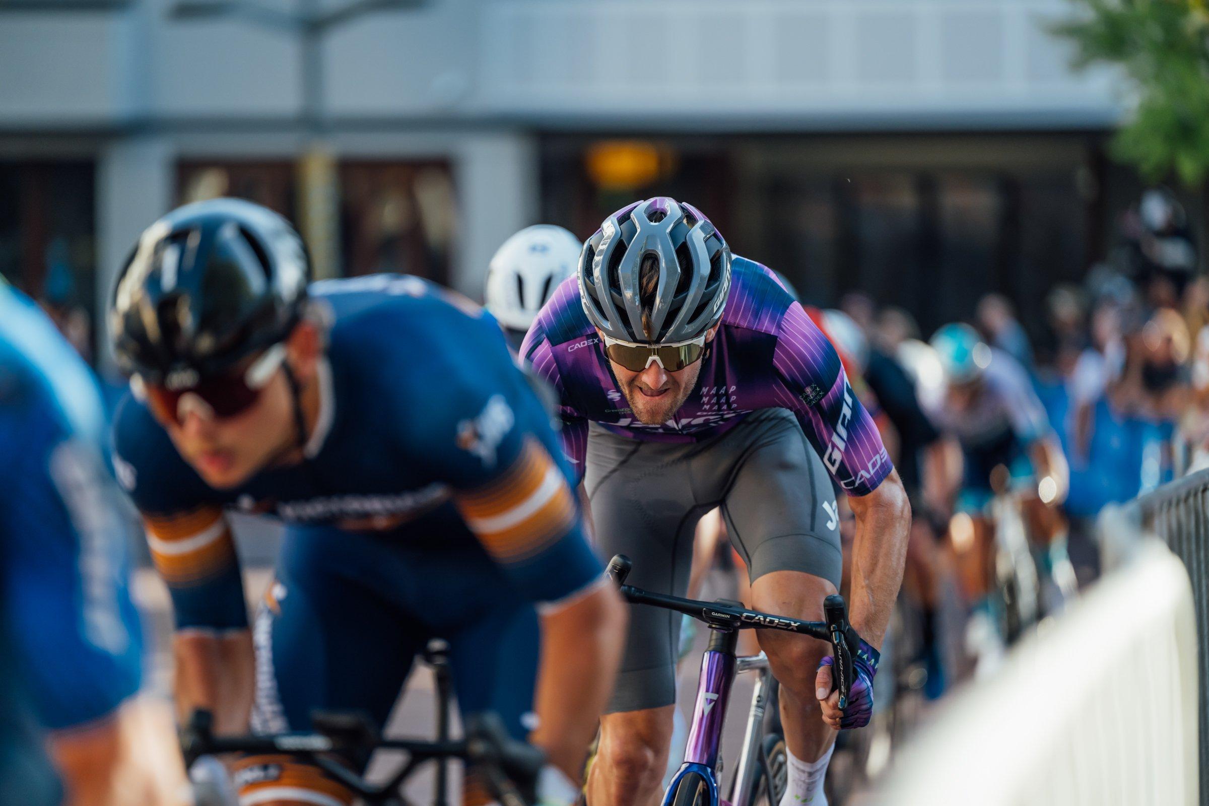 a group of cyclists riding down a street in a race