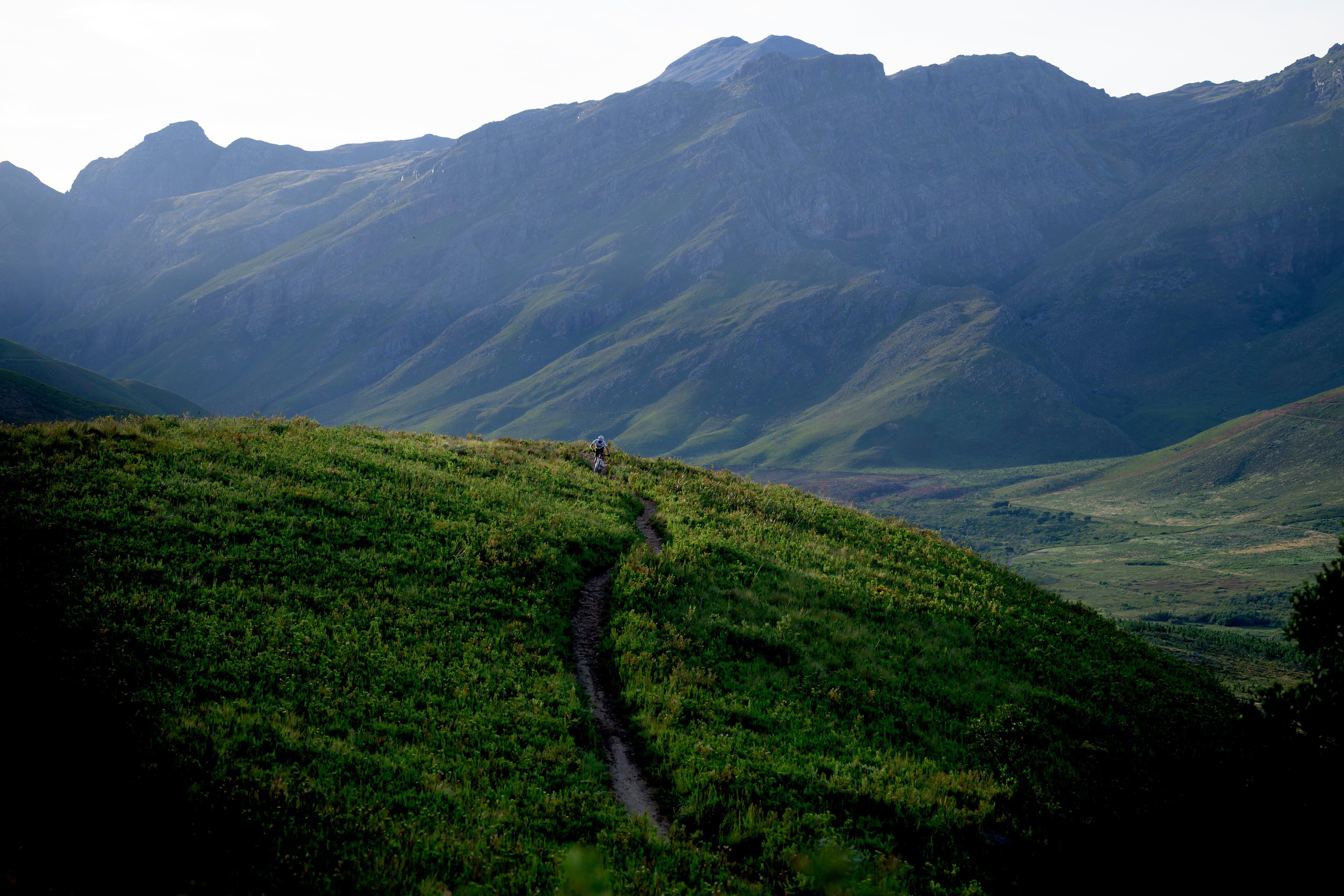 a person is walking on a trail in the mountains