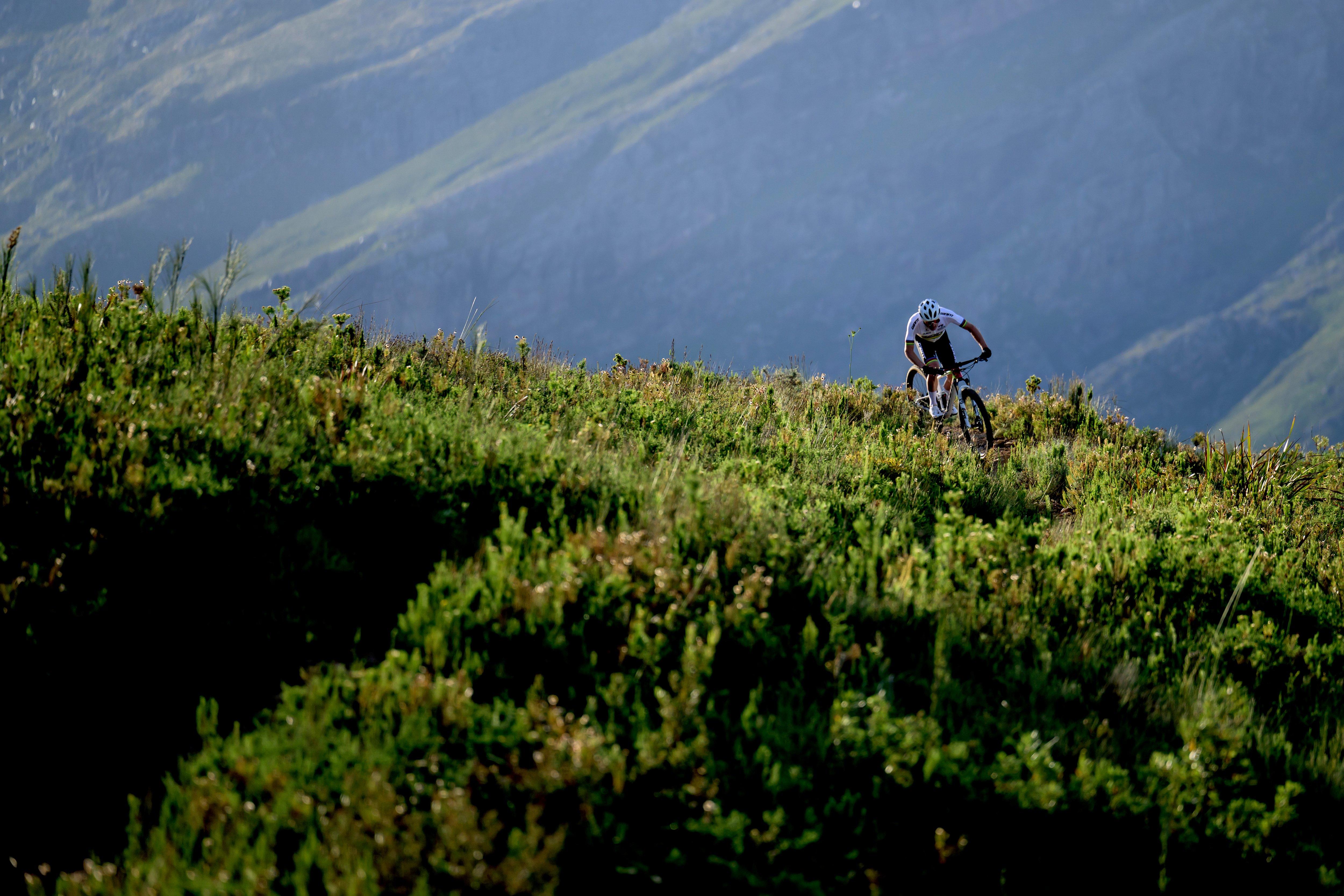 a person riding a mountain bike on a grassy hill