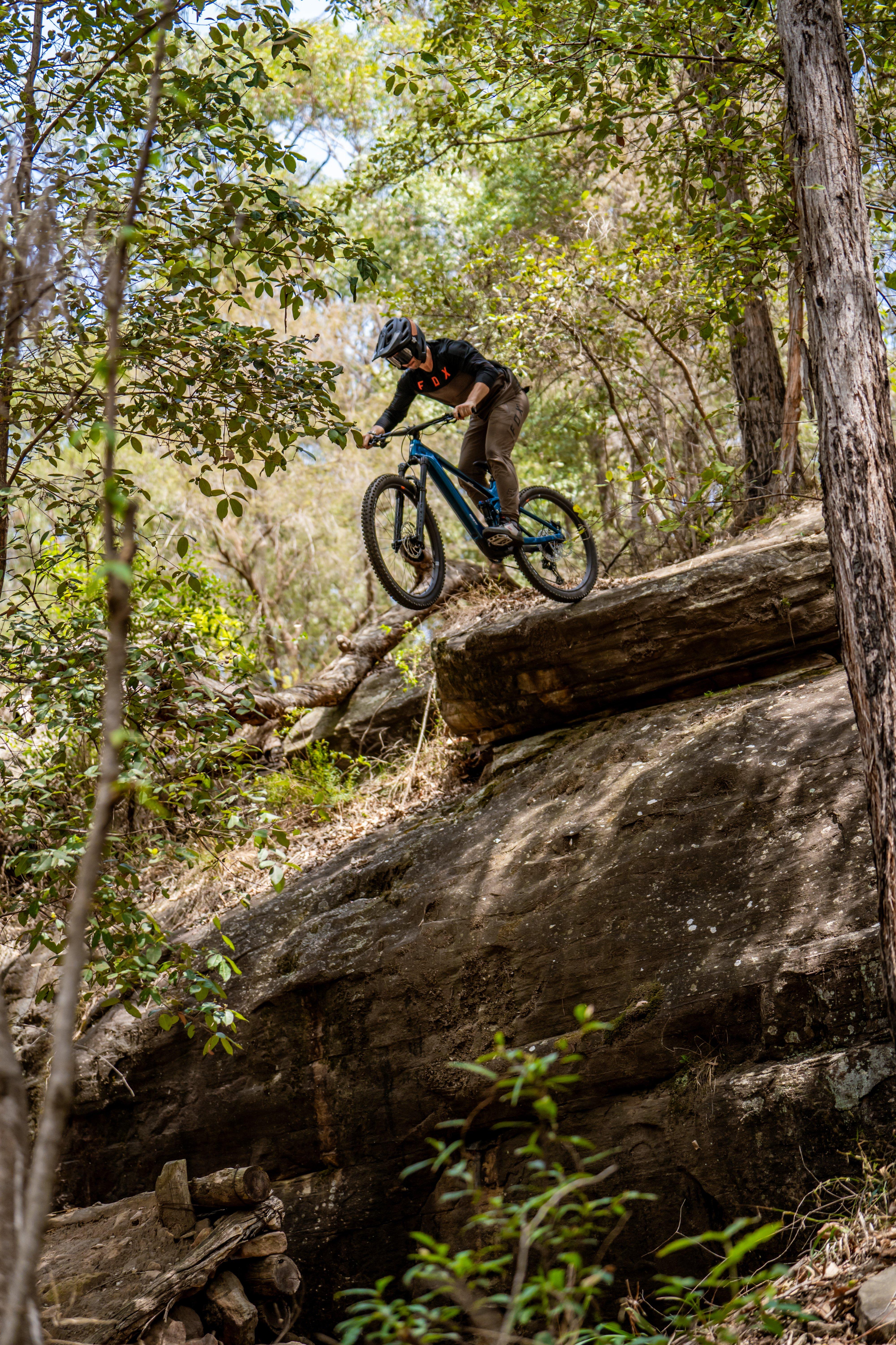 a mountain biker riding a bike over a large rock