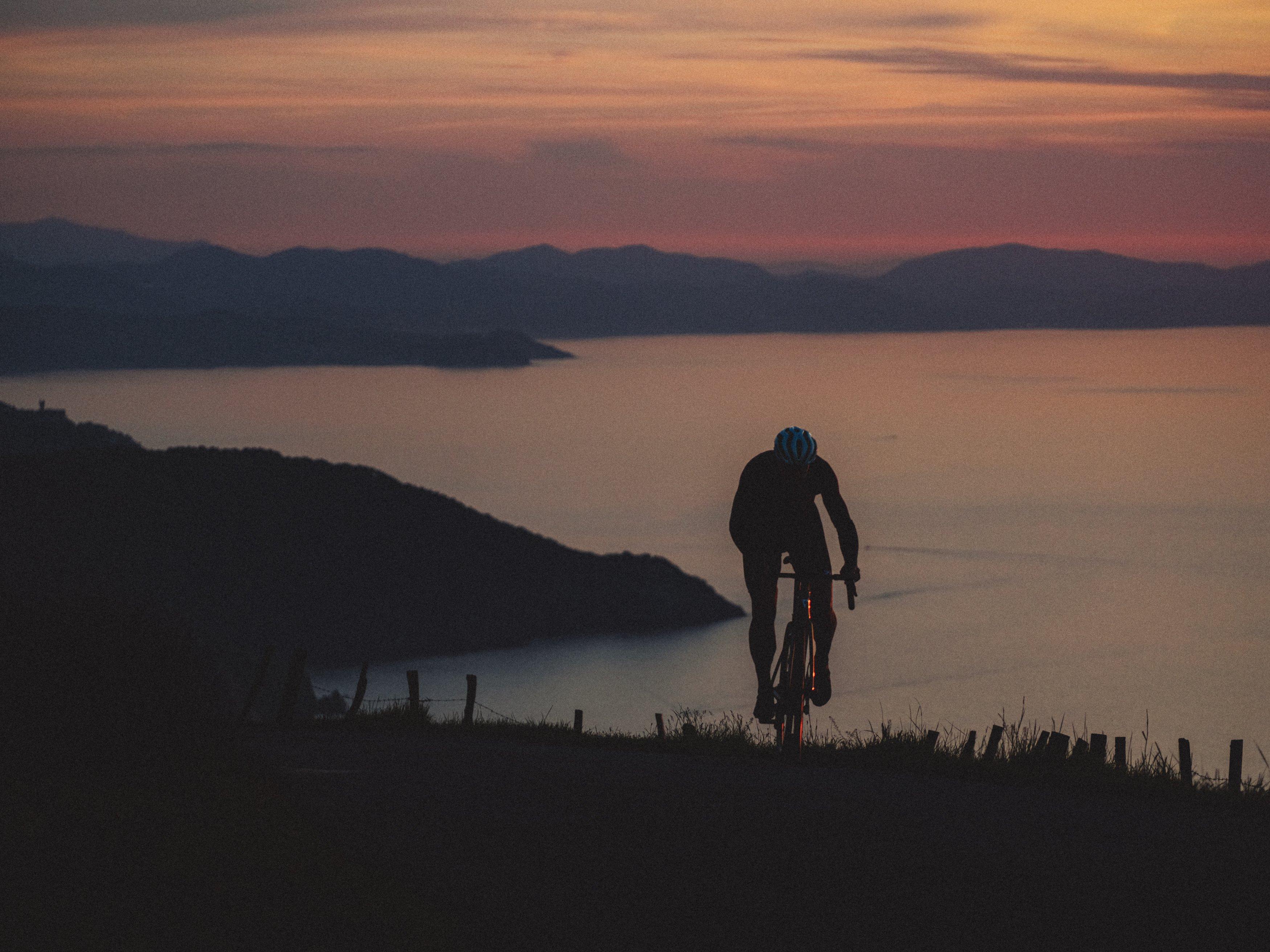 a person riding a bike on a hill overlooking the ocean