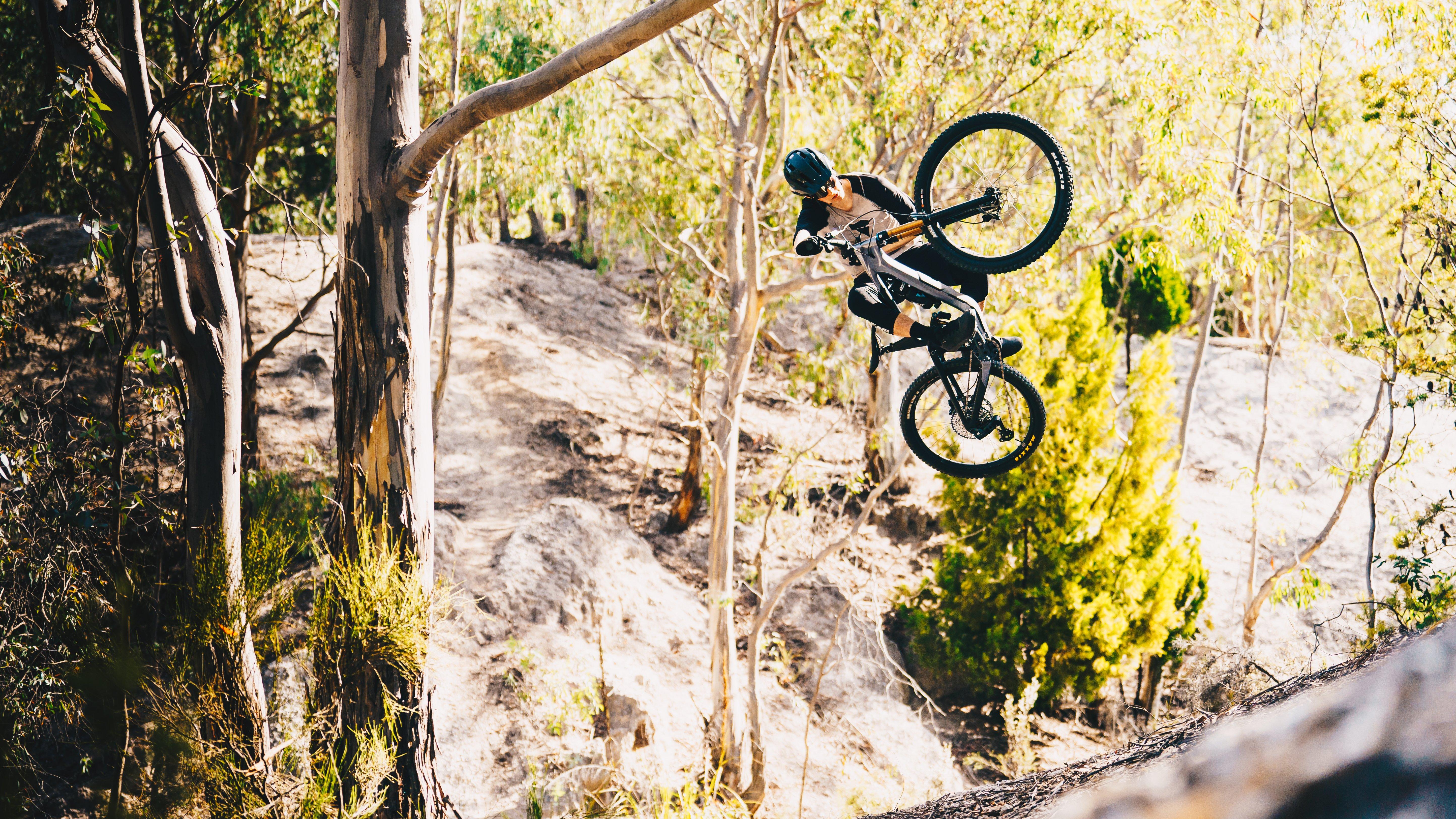 a person on a mountain bike jumping over a small hill