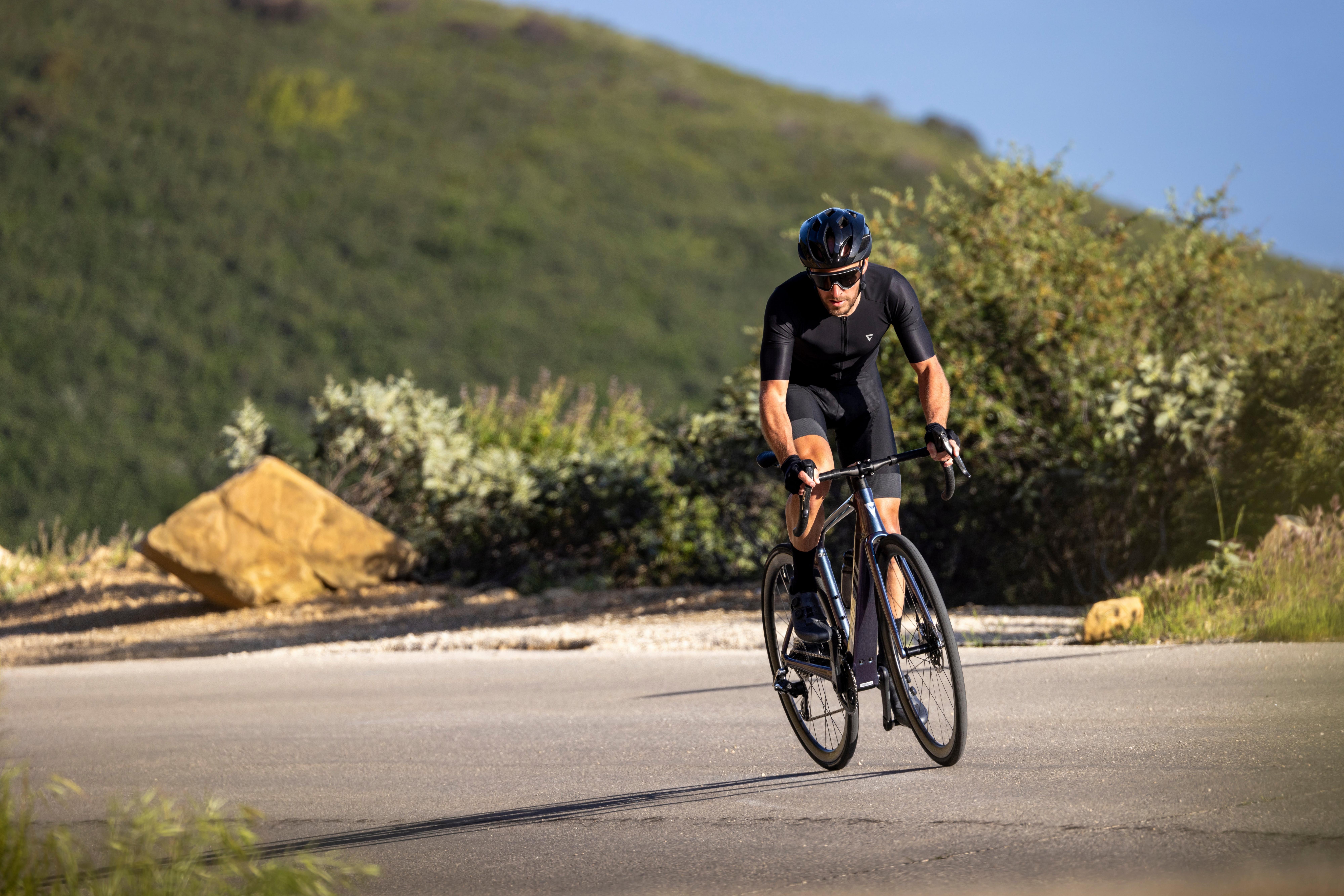 a man riding a bike on a road with a mountain in the background