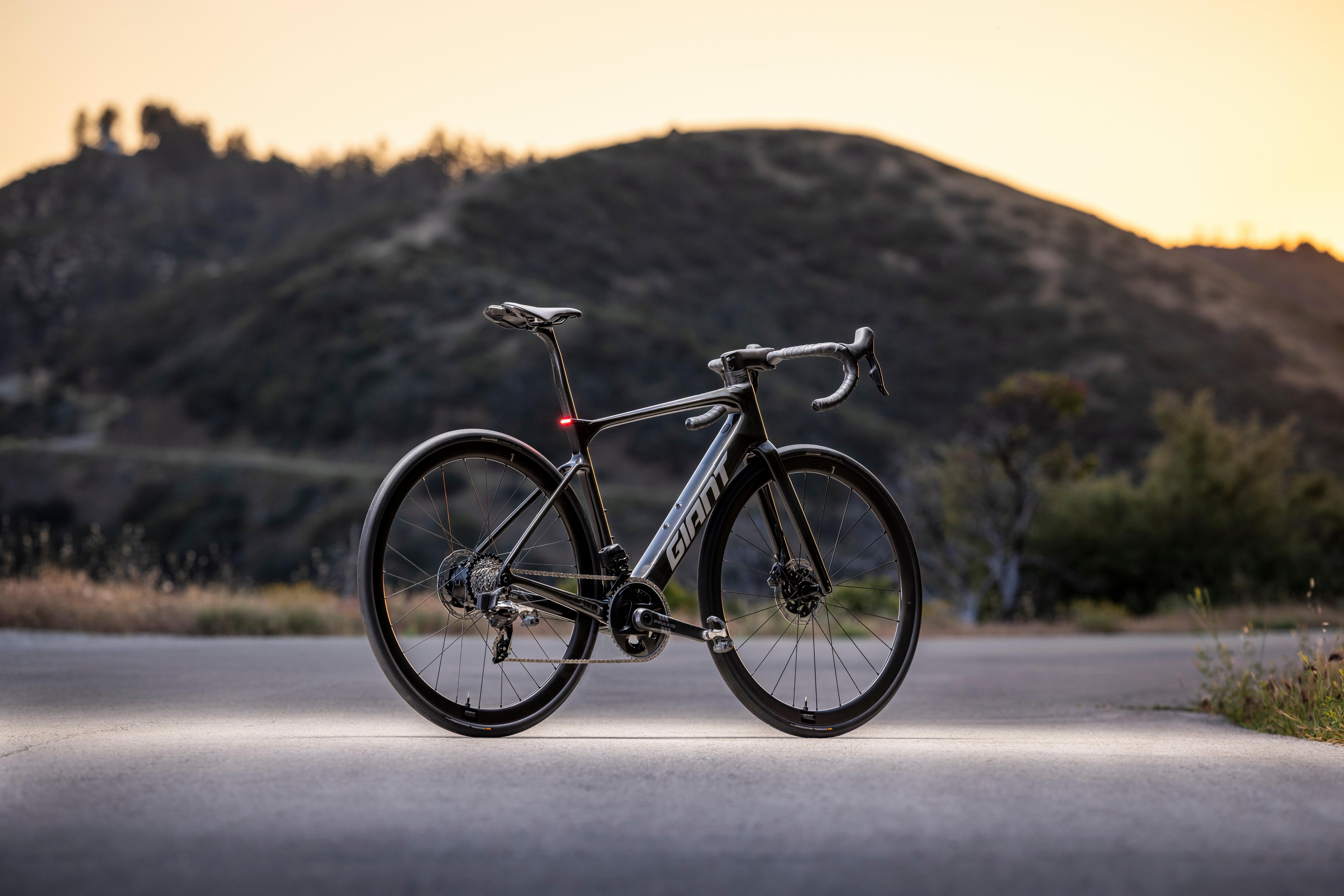 a black bike is parked on a road in the middle of the day