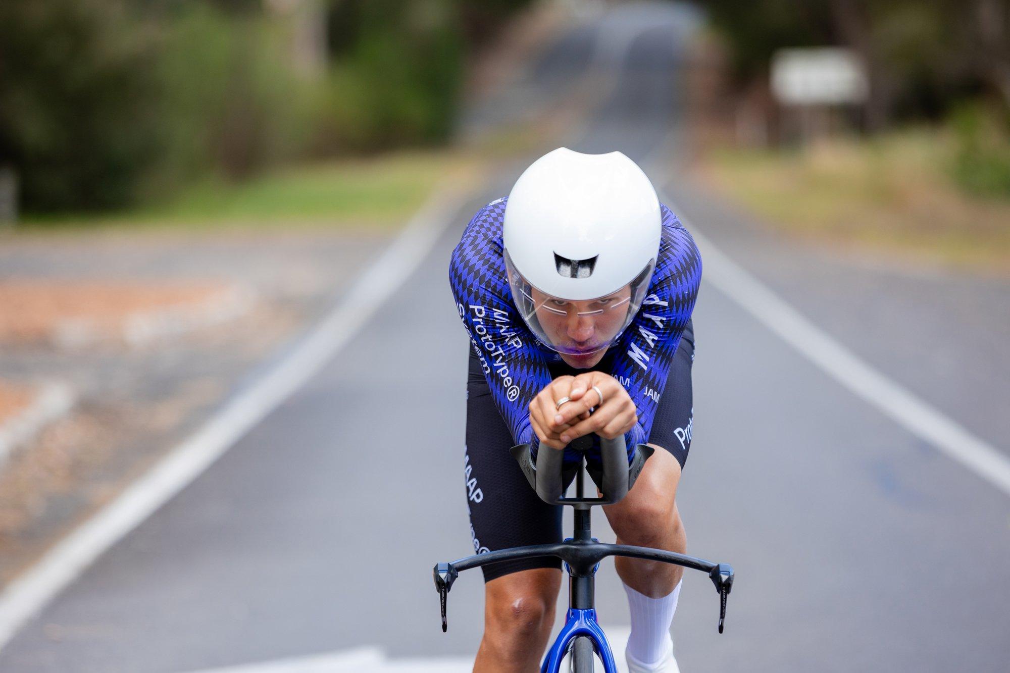 a man in a blue shirt and helmet riding a bike down a road
