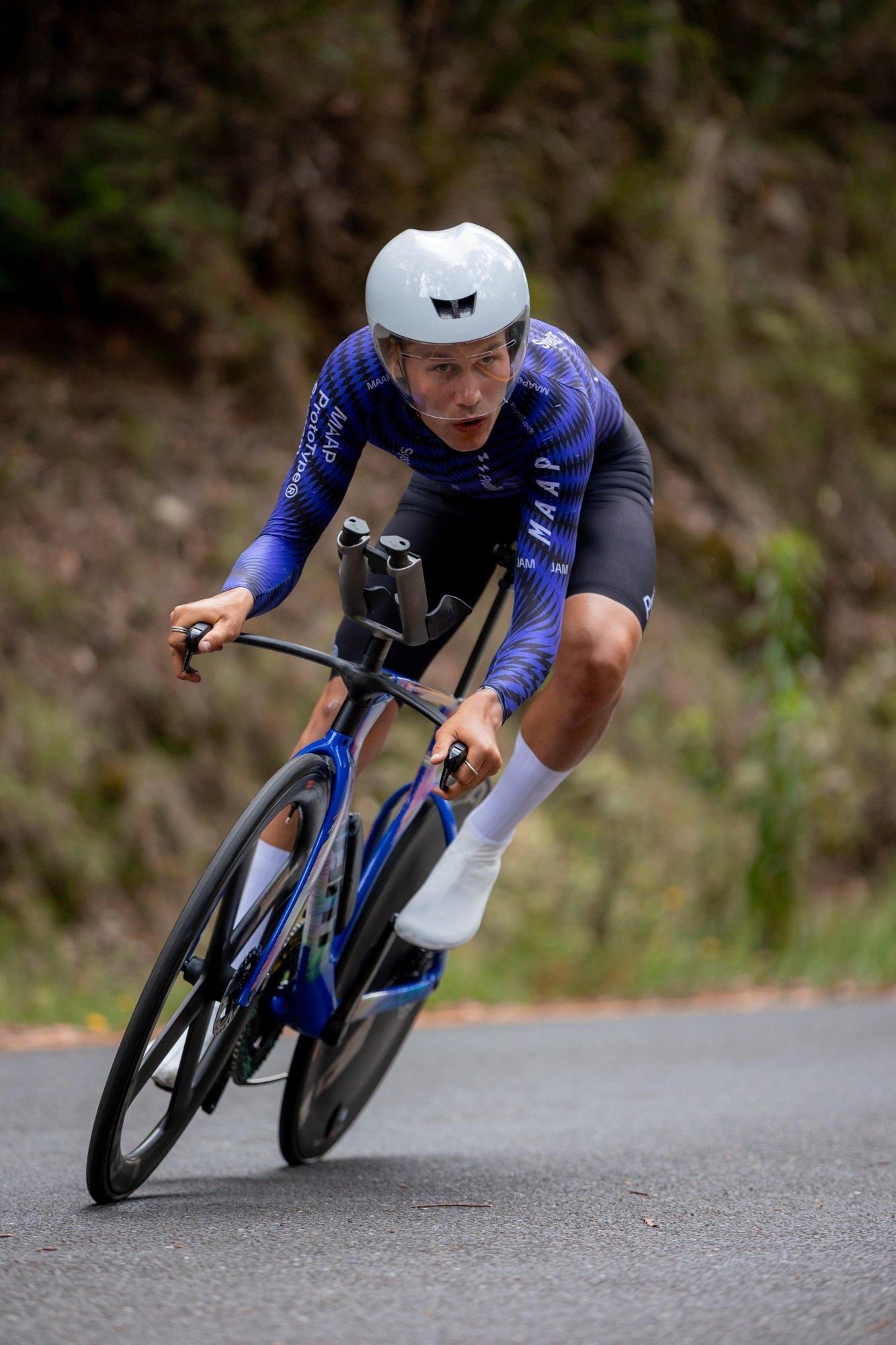 a man riding a bike down a road with a helmet on