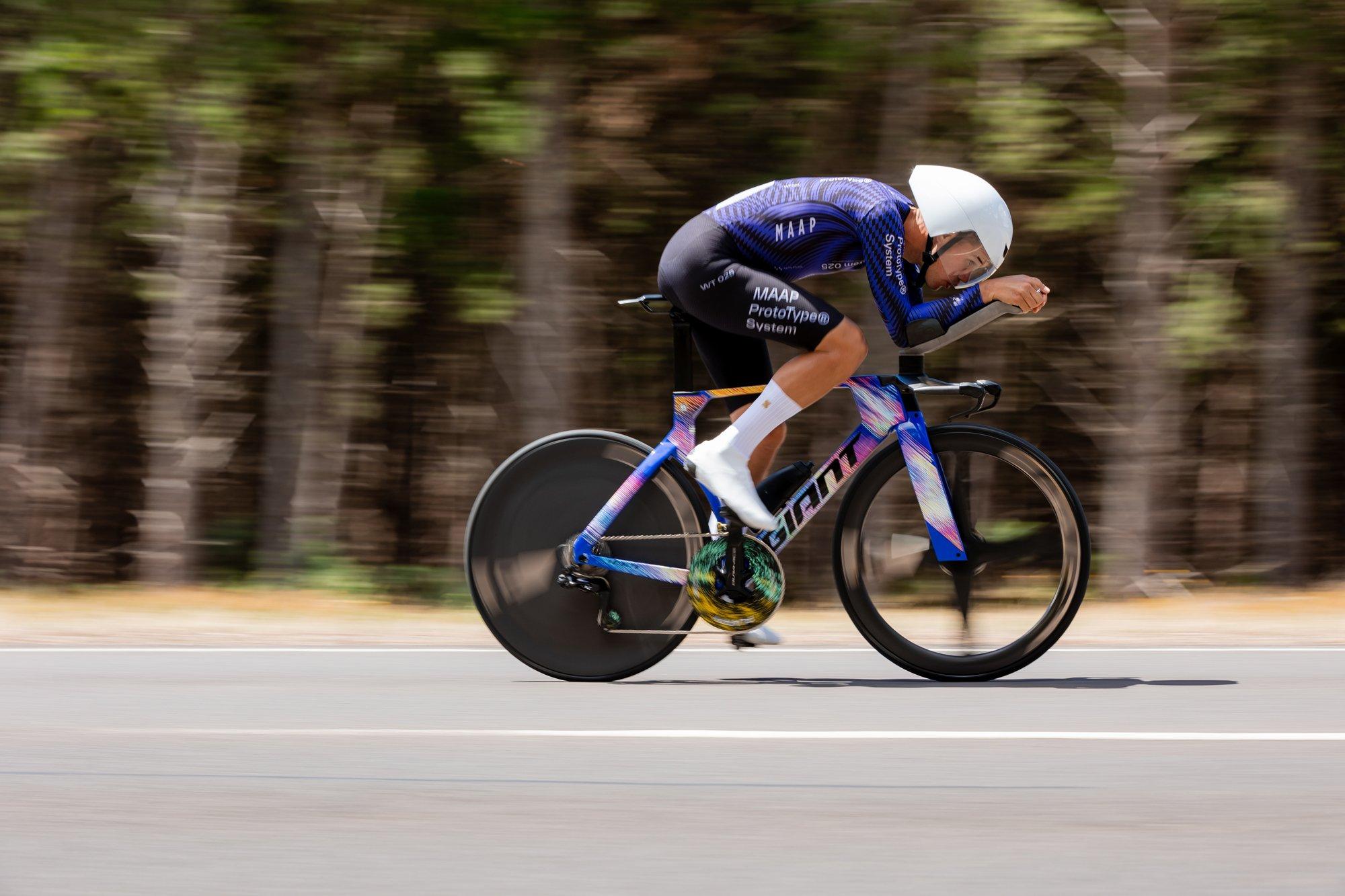 a man riding a bike on a road with trees in the background