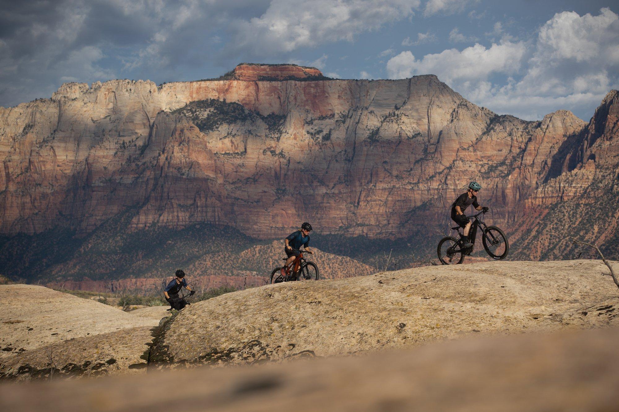 three people riding bikes on a rocky mountain top