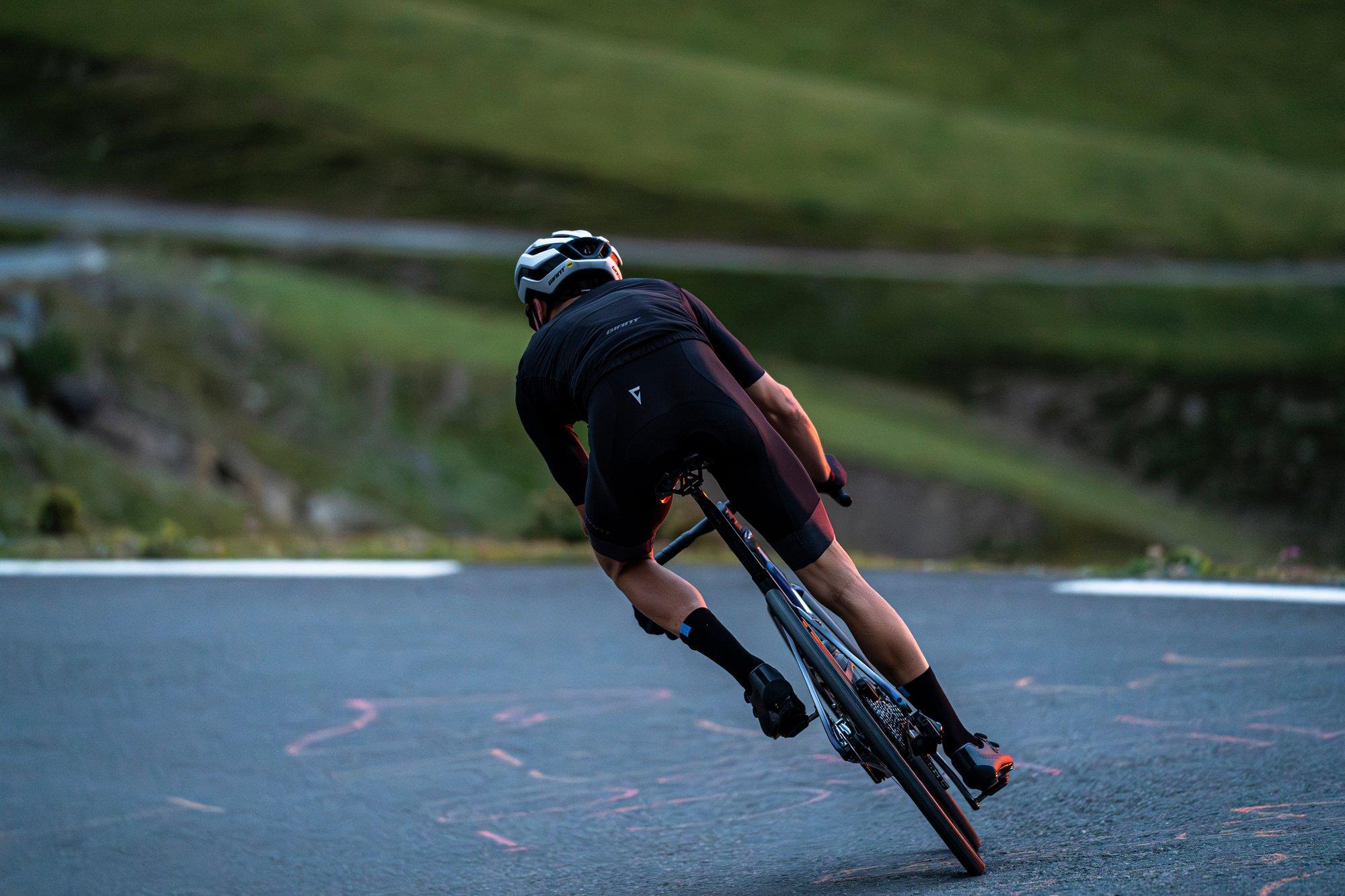 a man riding a bike down a hill on a paved road